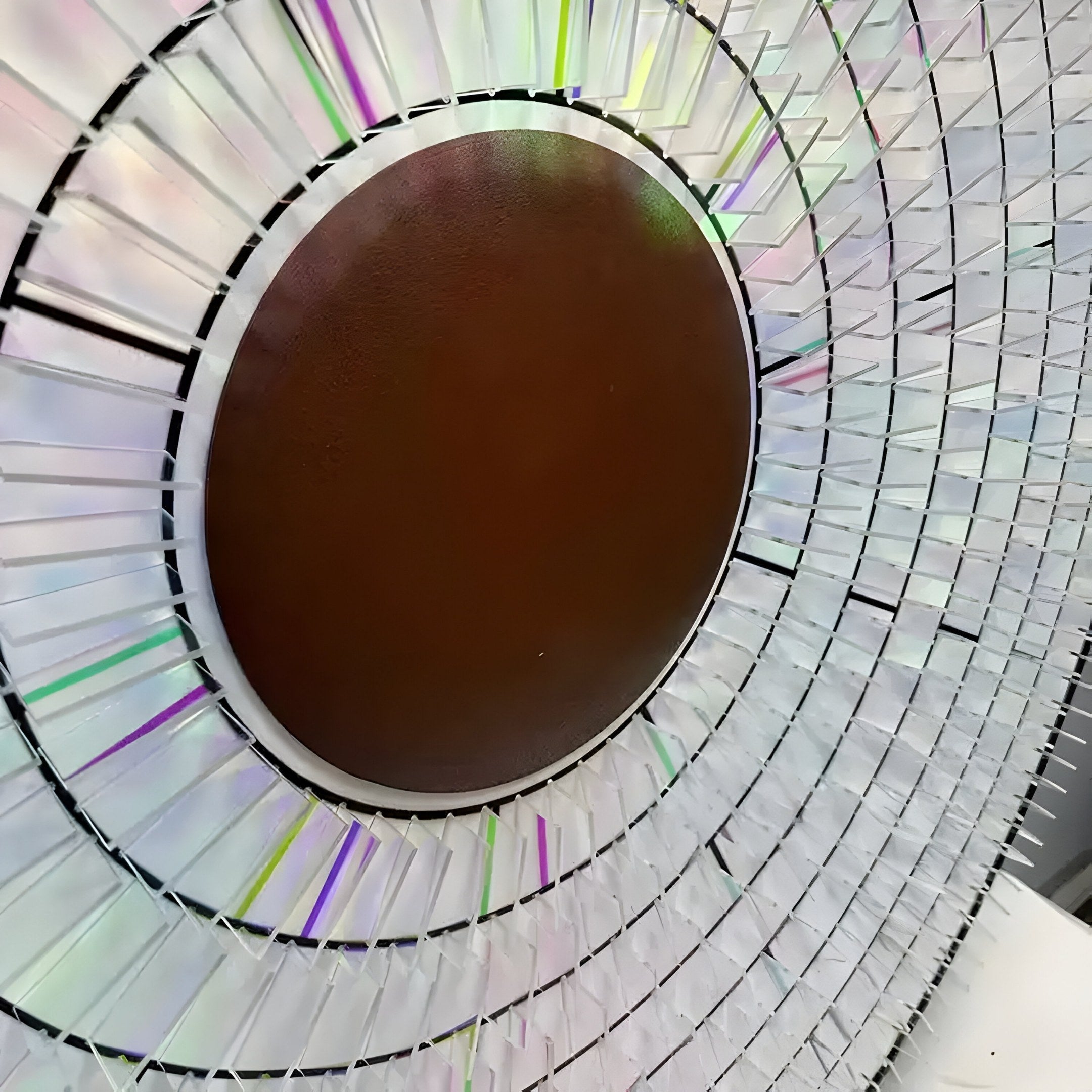 The Solis Radiant Deep Red Core Wood Relief 3D Wall Art by Giant Sculptures features a deep red core with layers of translucent, colorful acrylic panels. It reflects light in green, blue, and pink hues for an iridescent effect.