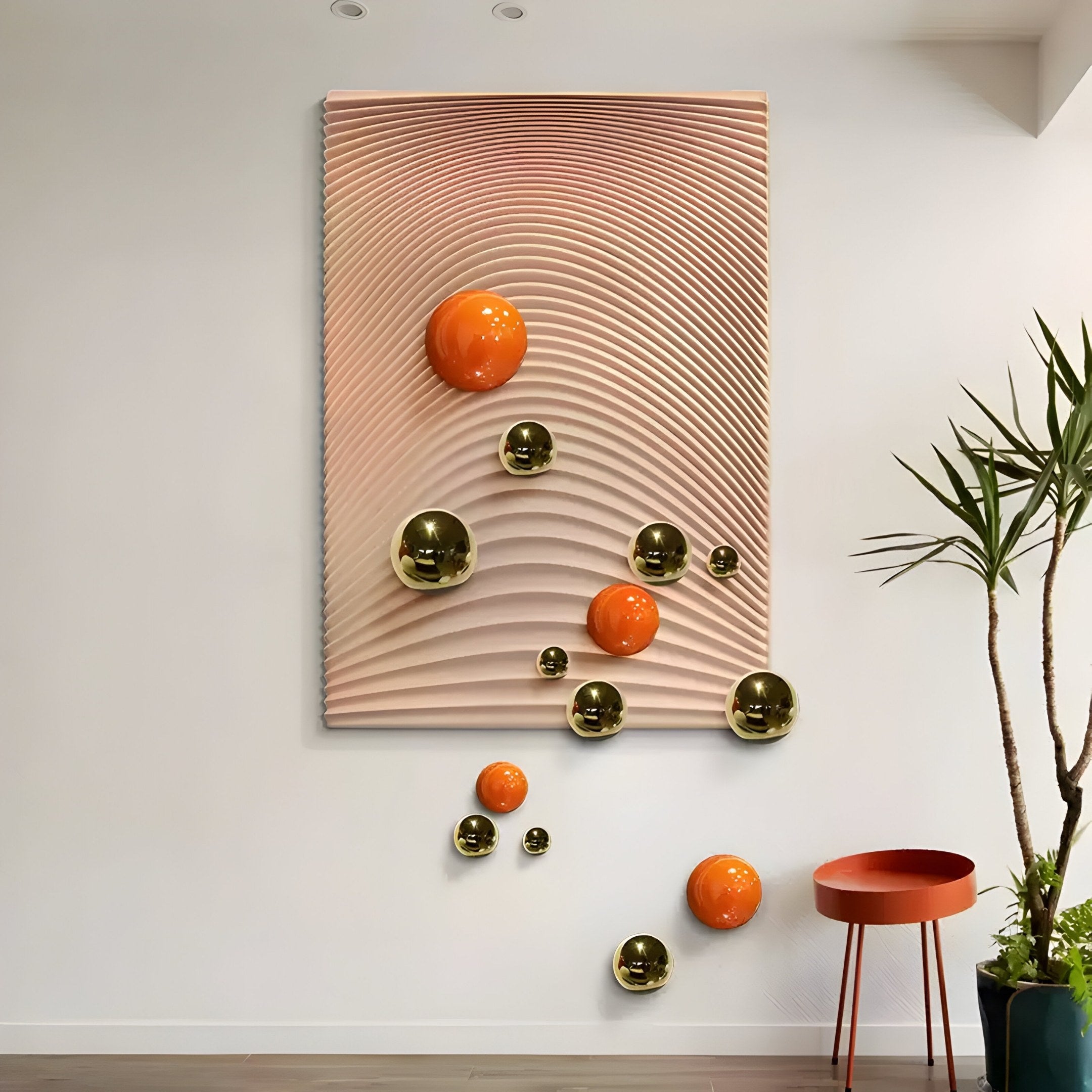 The Sphera Amber 3D Wood Relief Wall Art by Giant Sculptures features a wavy, ribbed beige background adorned with glossy gold and orange metal balls for a floating effect. A nearby potted plant and red stool on the wooden floor enhance its modern allure.