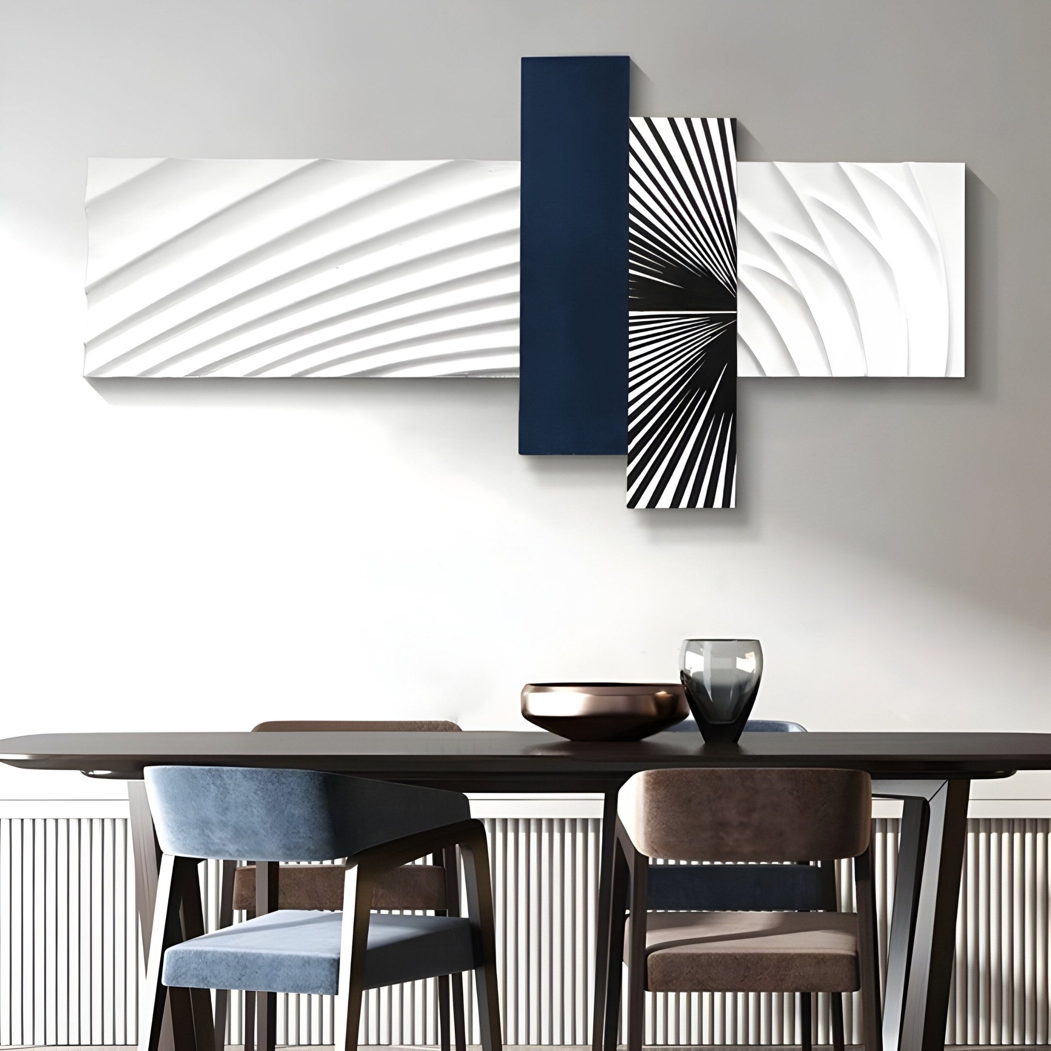A modern dining room features a dark wooden table with assorted chairs. Above, the Axentra Midnight Blue & White Geometric Wood Relief 3D Wall Art by Giant Sculptures hangs, showcasing monochrome geometric patterns and a vertical midnight blue rectangle, complemented by a stylish glass and metallic centerpiece.