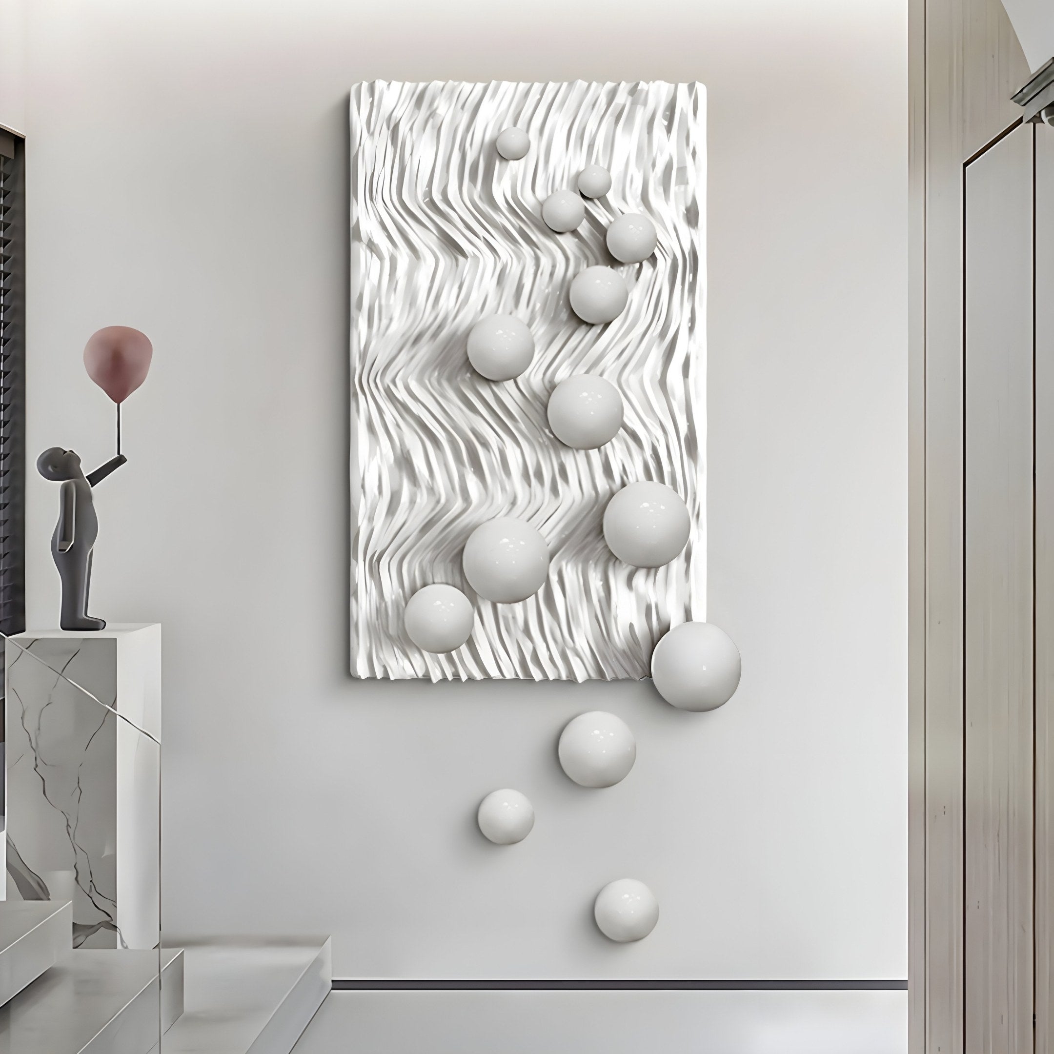 A stylish interior features the Fluxion White 3D Wood Relief Wall Art by Giant Sculptures, showcasing wavy patterns and spherical metal elements. A minimalist statue of a figure with a red balloon sits on the marble surface, enhancing the sleek design.