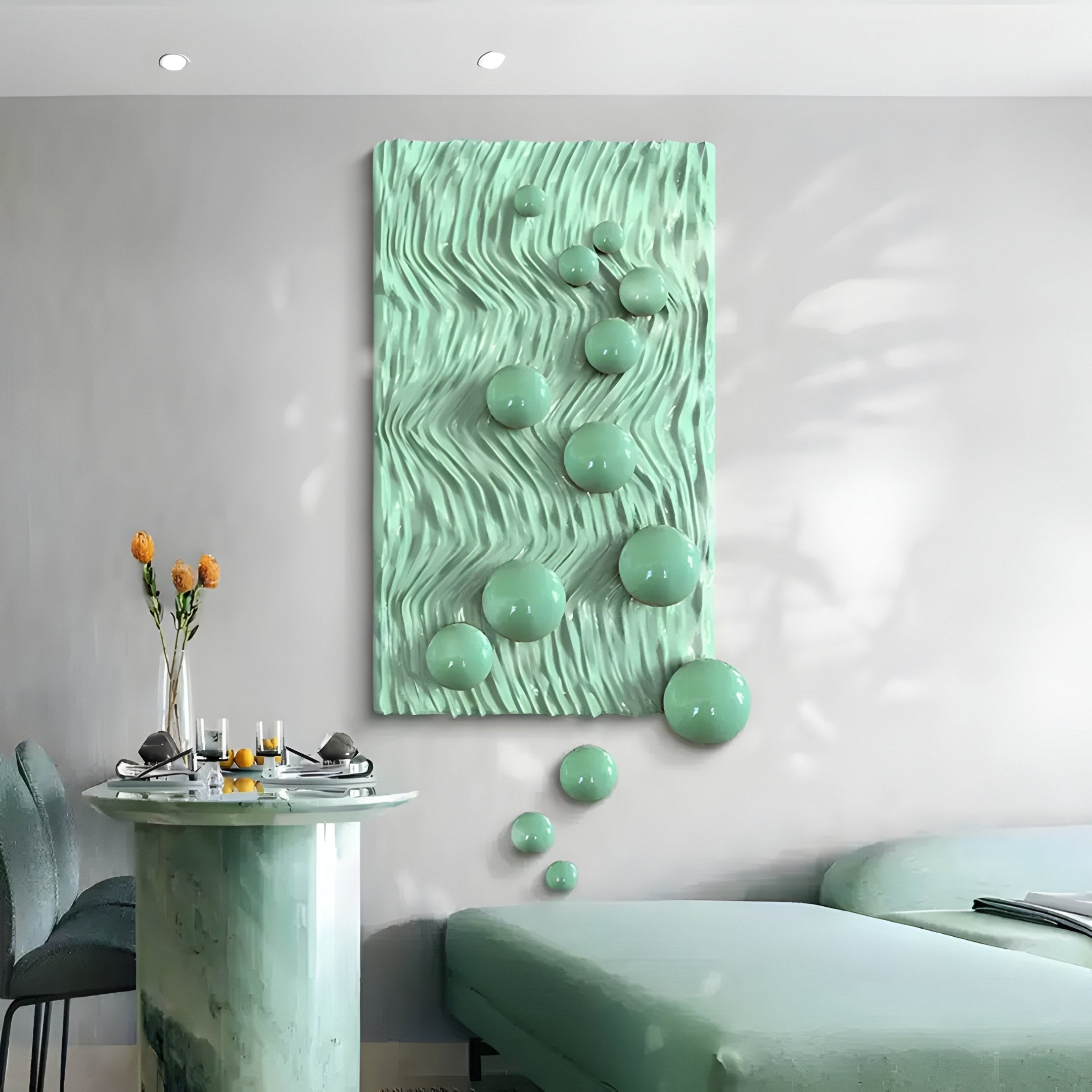 A modern living room features the Fluxion Mint Green 3D Wood Relief Wall Art With Metal Ball by Giant Sculptures. A small table with orange flowers and a dining set for two sits to the left, while a mint green curved couch completes the inviting space.