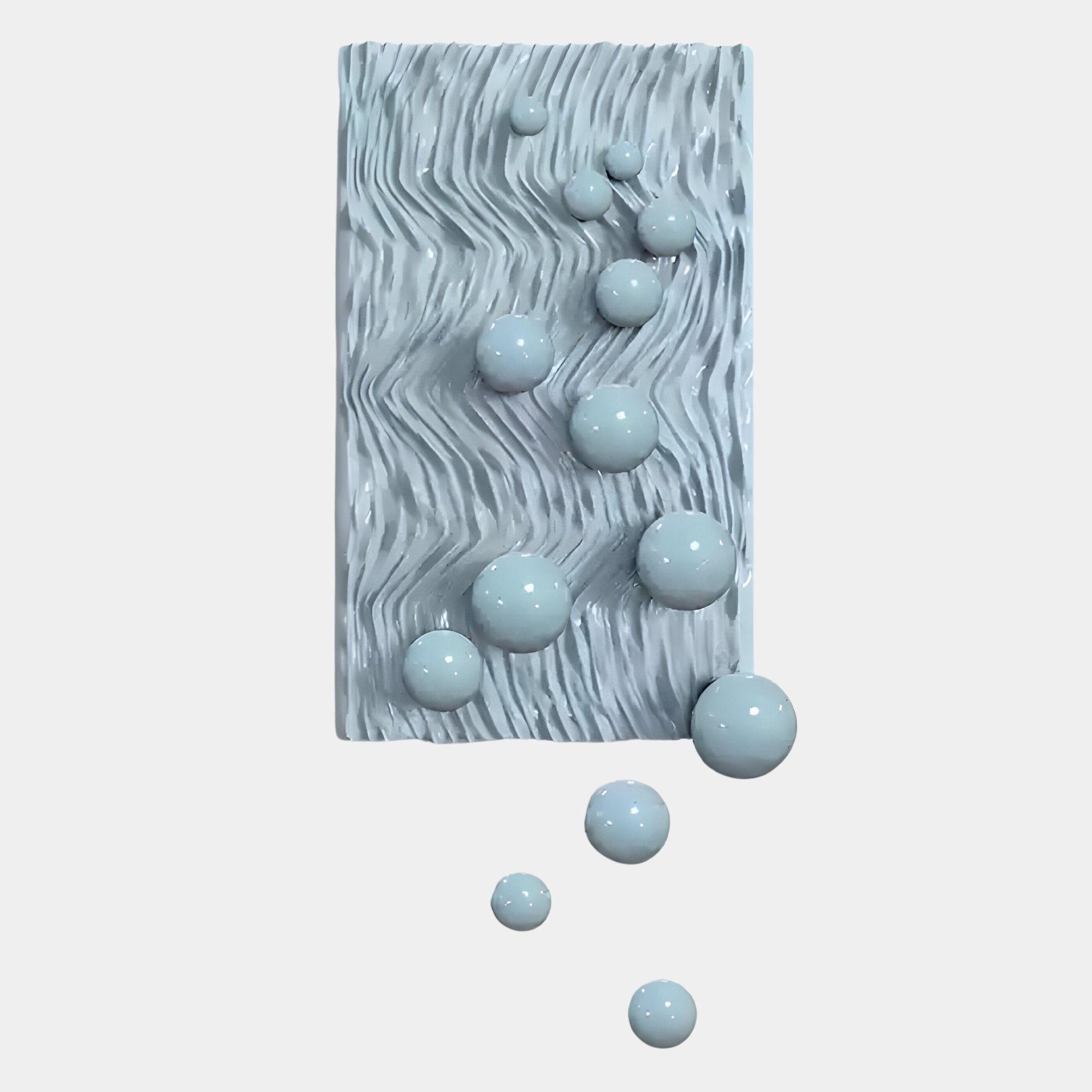 The Fluxion Soft Blue 3D Wood Relief Wall Art With Metal Ball by Giant Sculptures features a rectangular, textured blue panel with wavy grooves and glossy metal spheres of varying sizes emerging from the surface.