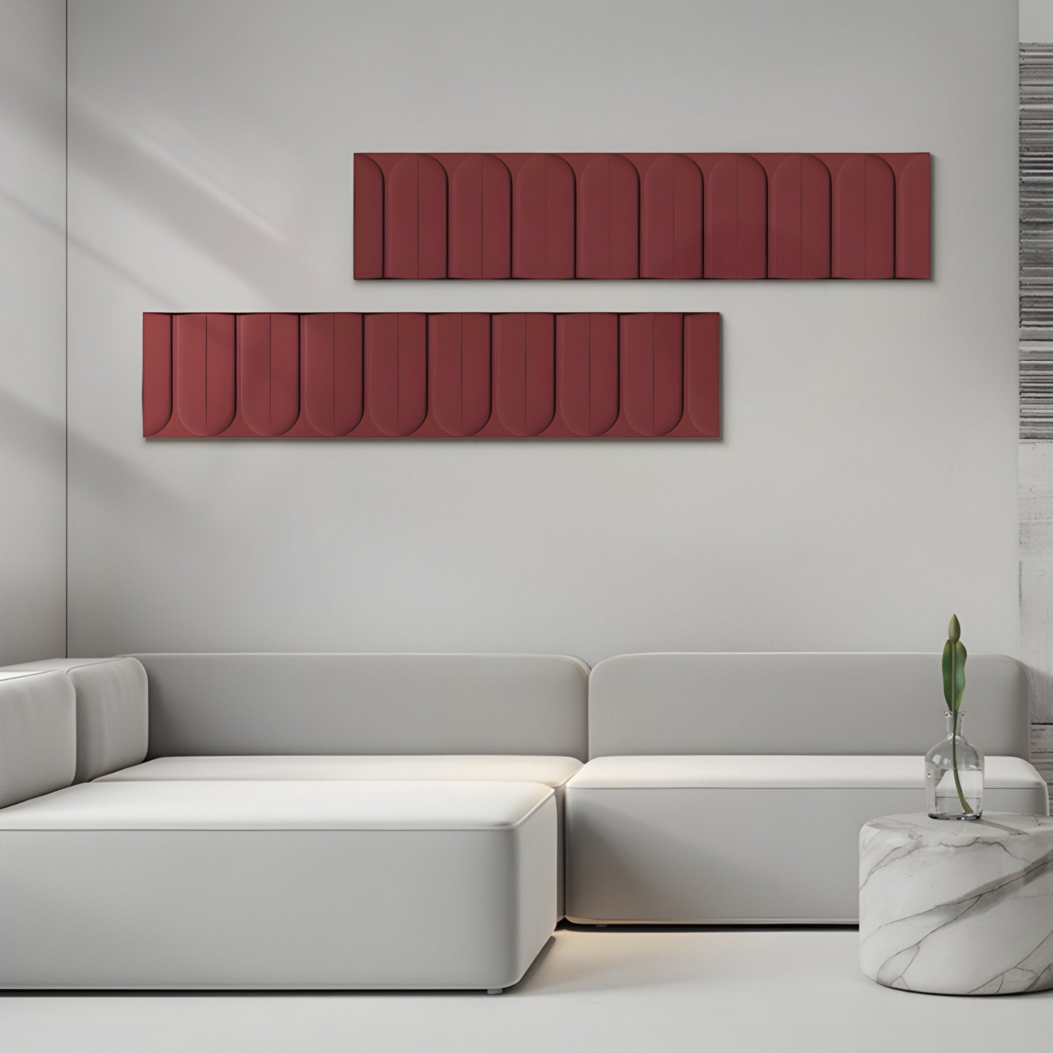 A minimalist living room includes a white corner sofa beneath two Vireus Burgundy Rectangular 3D Wood Relief Wall Panels by Giant Sculptures. A marble side table displays a single-stem plant in a glass vase, and the space is naturally lit, exuding an inviting and serene atmosphere.
