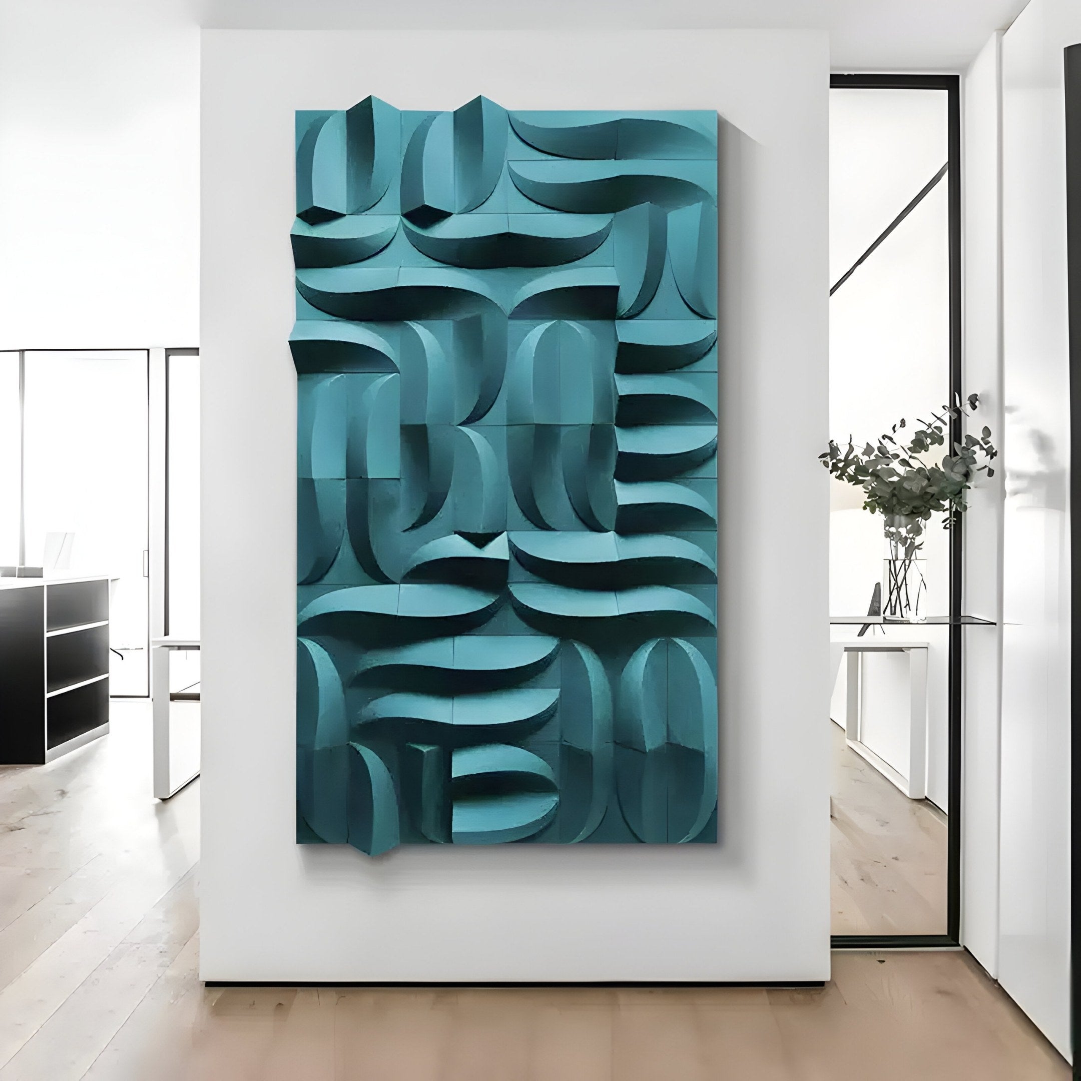 The Ombra Teal Blue Hand-Painted Sandstone 3D Wood Relief Wall Art by Giant Sculptures features an abstract geometric design with interlocking blue and turquoise shapes, perfect for display on a white wall in a minimalist interior with wooden floors and glass partitions.