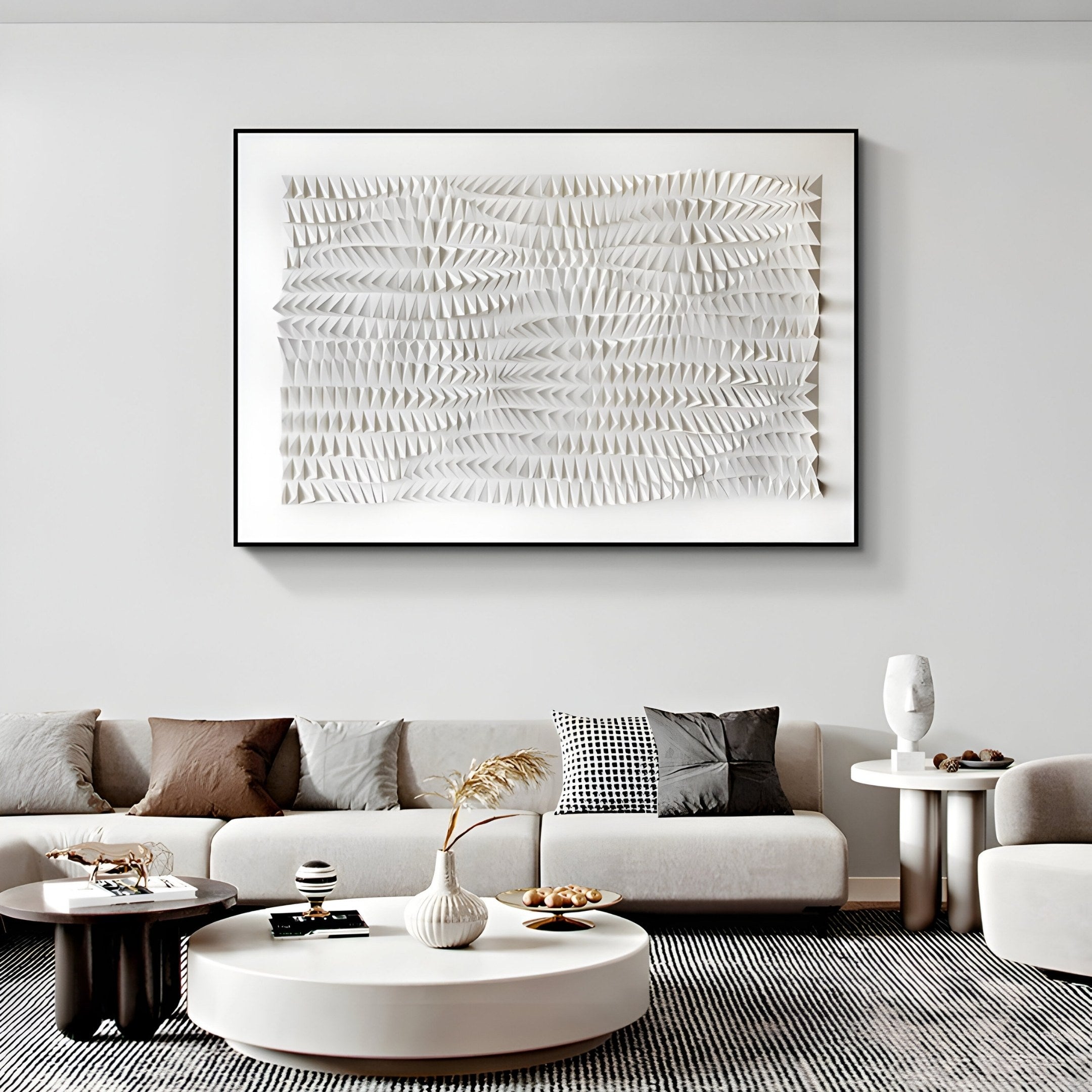 A modern living room showcases a neutral-toned sofa with assorted pillows, a textured coffee table, and is highlighted by the Elytrum White Hand-Painted Wood Relief 3D Wall Art by Giant Sculptures. Decorative objects and a plant in vases complete the stylish minimal décor.