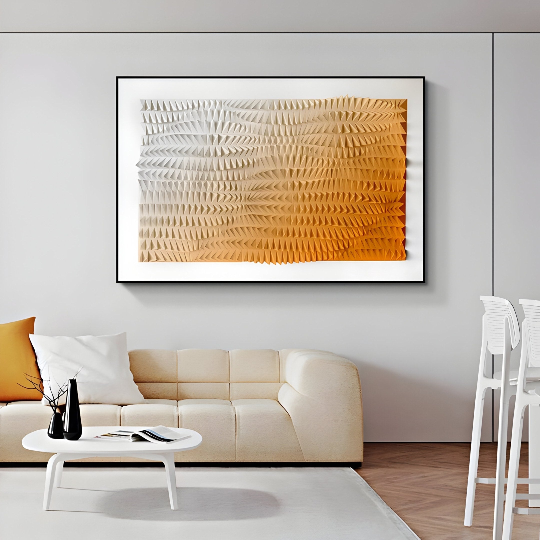 A minimalist living room includes a cream sofa, white cushions, a small white coffee table with a black vase, and is adorned with the Elytrum Orange Gradient Hand-Painted Wood Relief 3D Wall Art by Giant Sculptures. To the right, there are white bar stools that complement the serene setup.