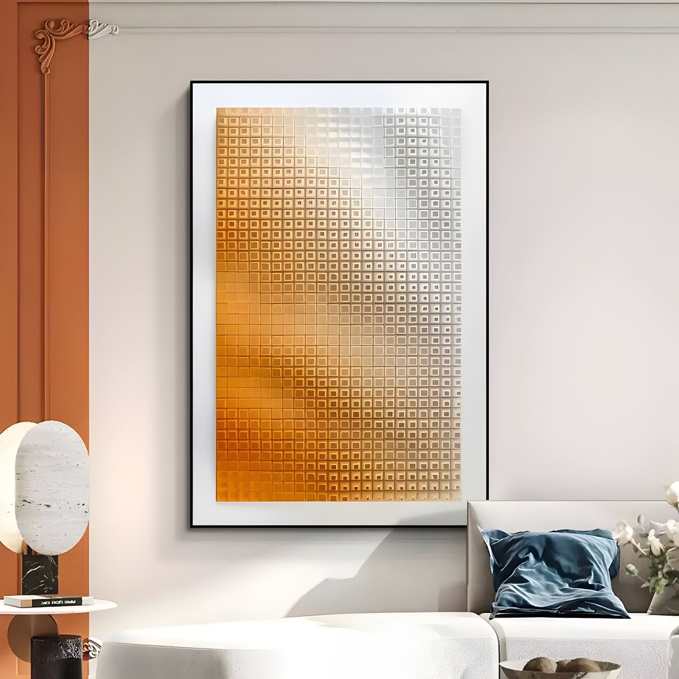 A modern living room features the Elytrum Orange Grid Gradient Hand-Painted Wood Relief 3D Wall Art by Giant Sculptures, showcasing a striking grid of orange and silver tones. The half-painted orange wall beautifully complements the white table and beige sofa with blue cushions for a harmonious style blend.