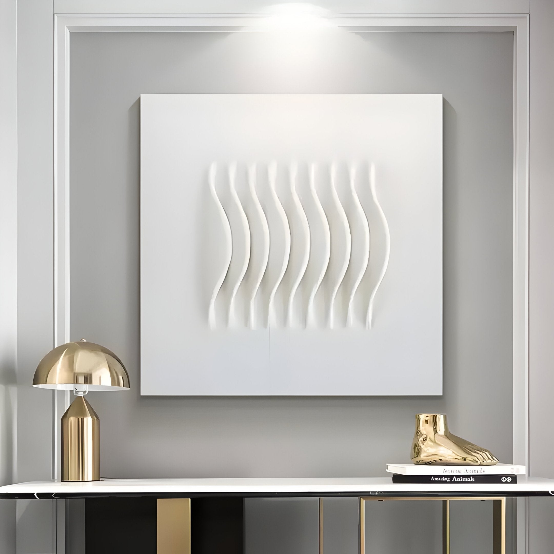 In a modern interior, the Ondara Wave White Square Wood Relief 3D Wall Art by Giant Sculptures takes center stage with its minimalist design. A white console below holds a gold accent lamp, book stack, and gold shoe sculpture, with chic metallics elevating the neutral palette.