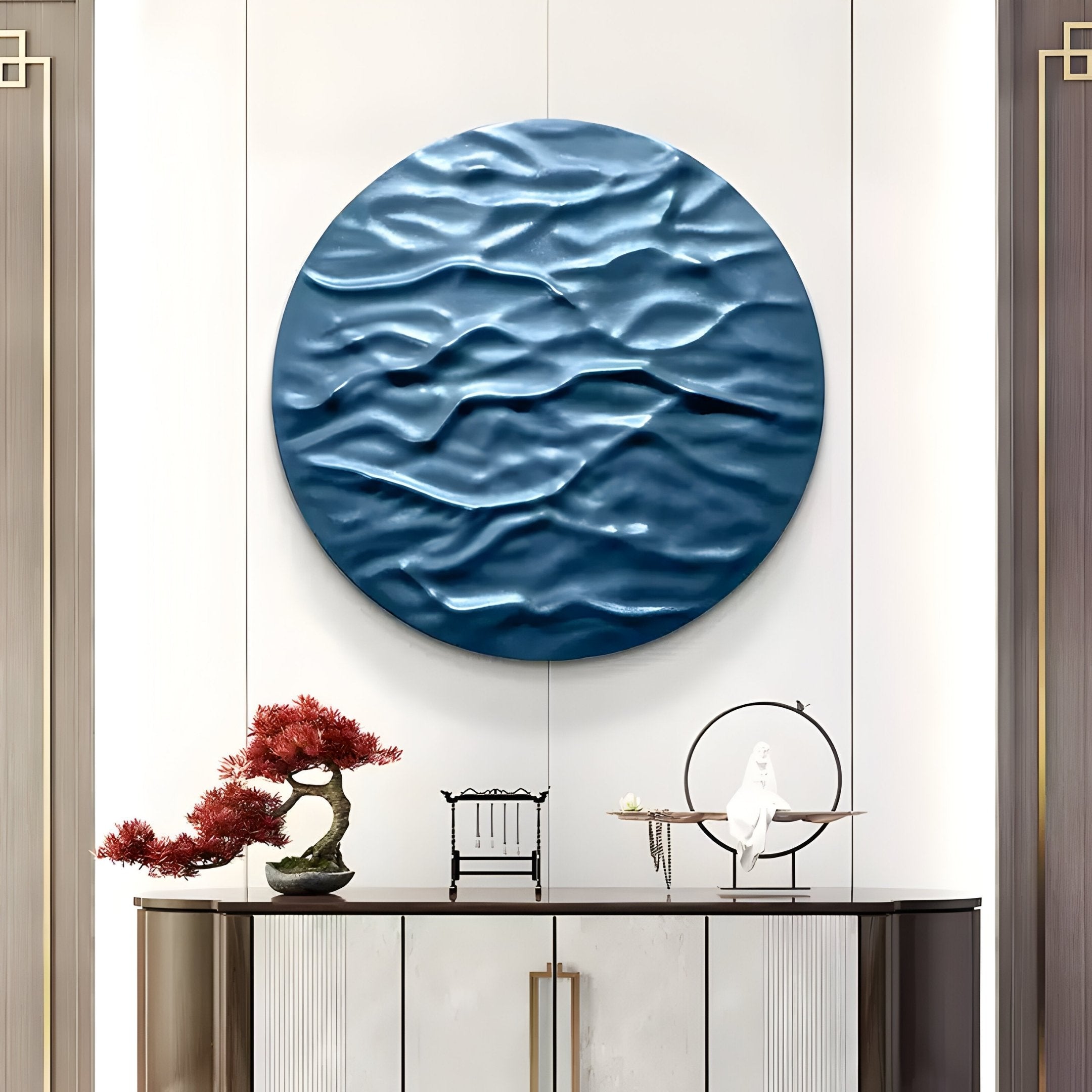 The Orenda Ripple Wave Blue Wood Relief 3D Wall Art by Giant Sculptures adorns a white wall above a modern console, which hosts a bonsai tree, model chair, and elegant bird sculpture. This decor exudes Japanese minimalist aesthetics and sophistication.