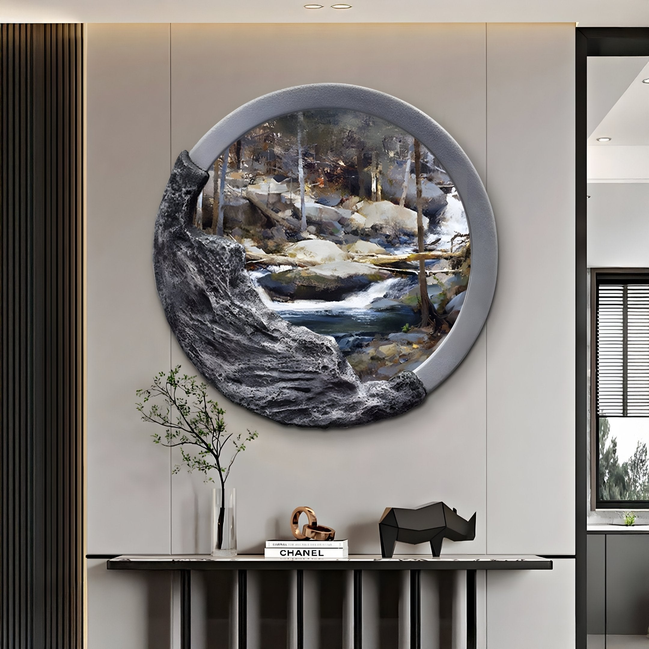 A modern interior features a circular Sylvara Forest Stream Hand-Painted Wood Relief 3D Wall Art by Giant Sculptures, evoking serene nature. Below, a console table holds a bonsai, rhinoceros figure, and the book Chanel.