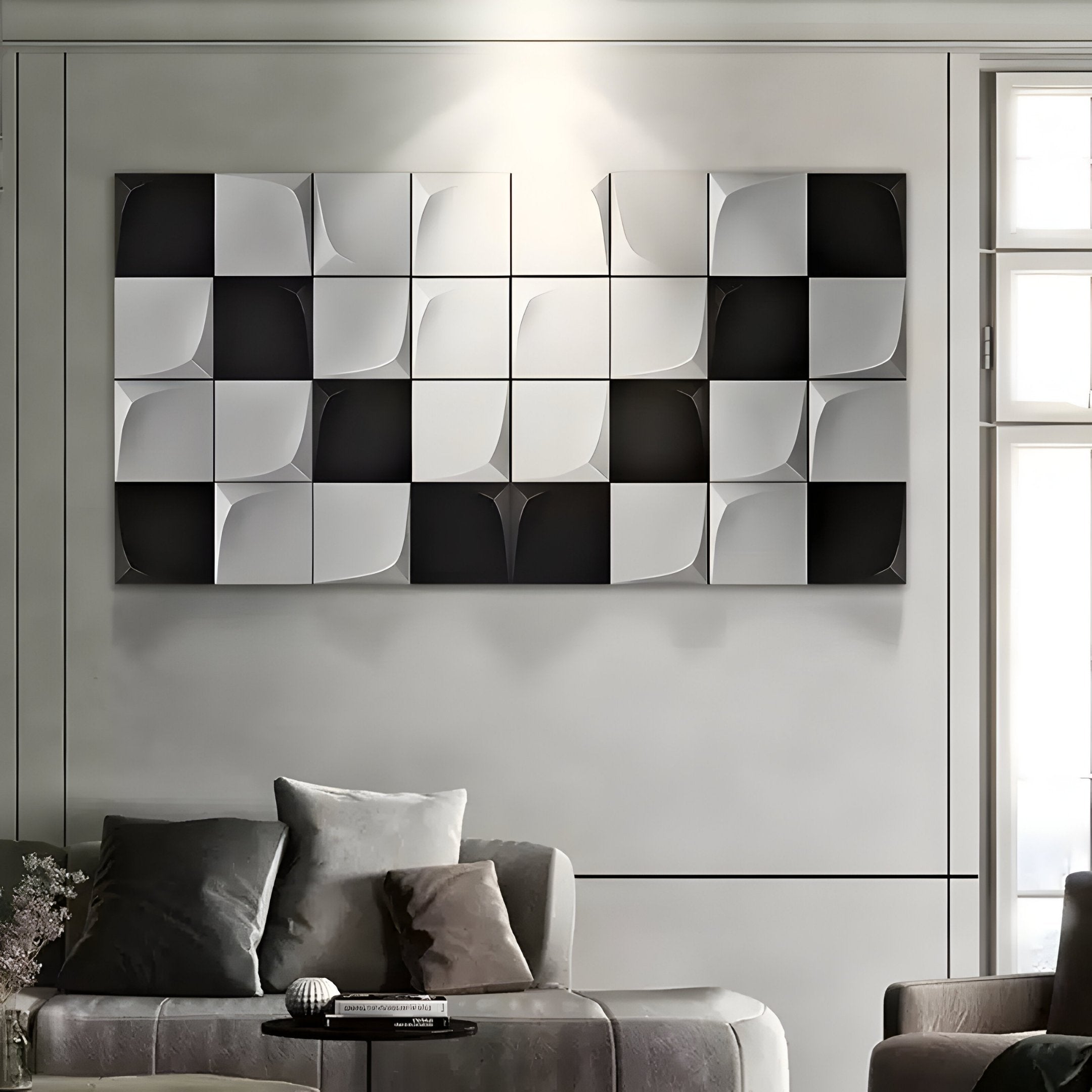 A modern living room features the Averra White & Black Geometric Wood Relief 3D Wall Art by Giant Sculptures, enhancing the monochrome decor. A gray sofa with matching cushions sits below, while natural light from a window illuminates a small table in front of the sofa.
