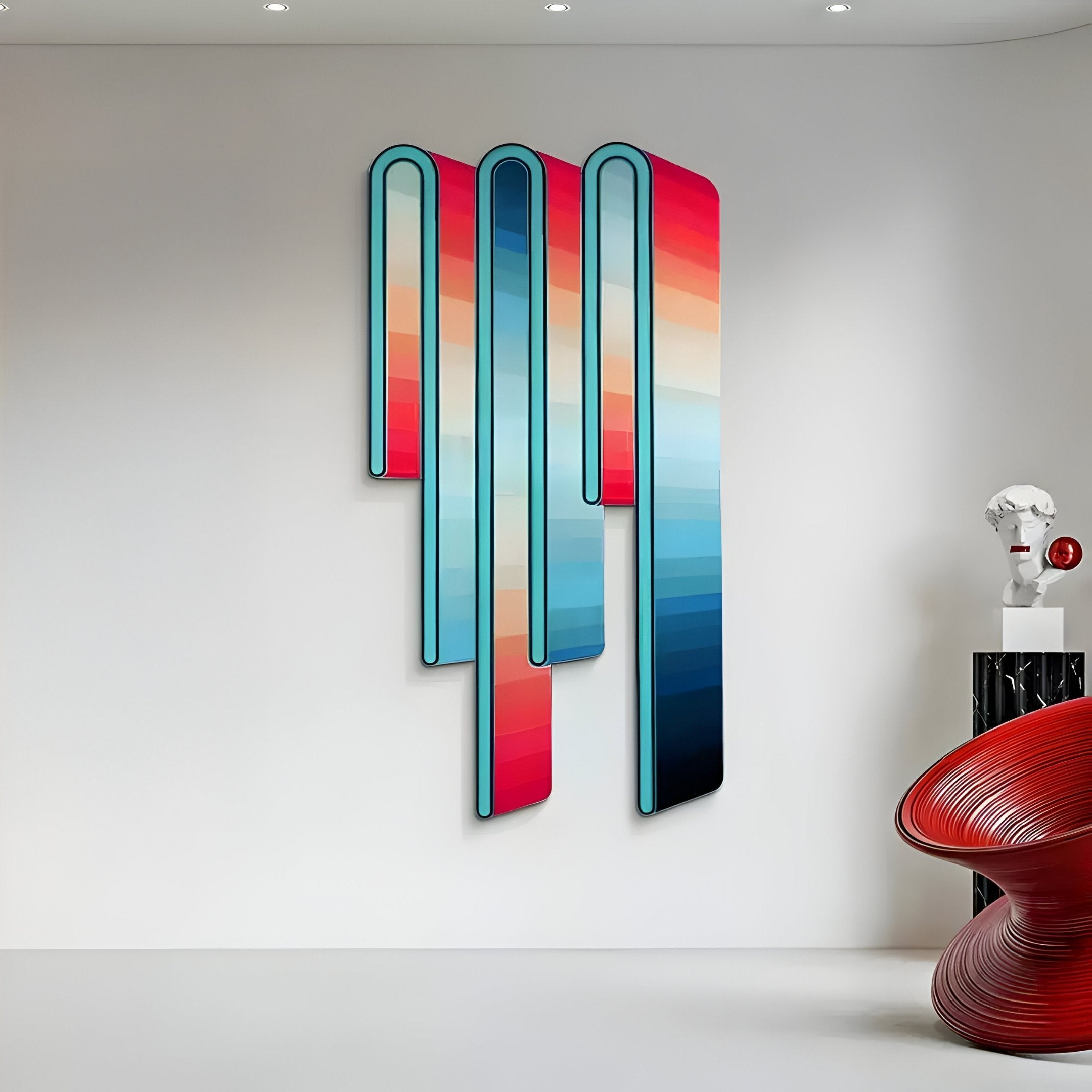 The Giant Sculptures Opaline Coral Teal Gradient Wood Relief 3D Wall Art displays multicolored vertical panels transitioning from red to blue, mounted on a light gray wall, with a modern red ribbed chair on the right and a small sculpture atop a white pedestal.