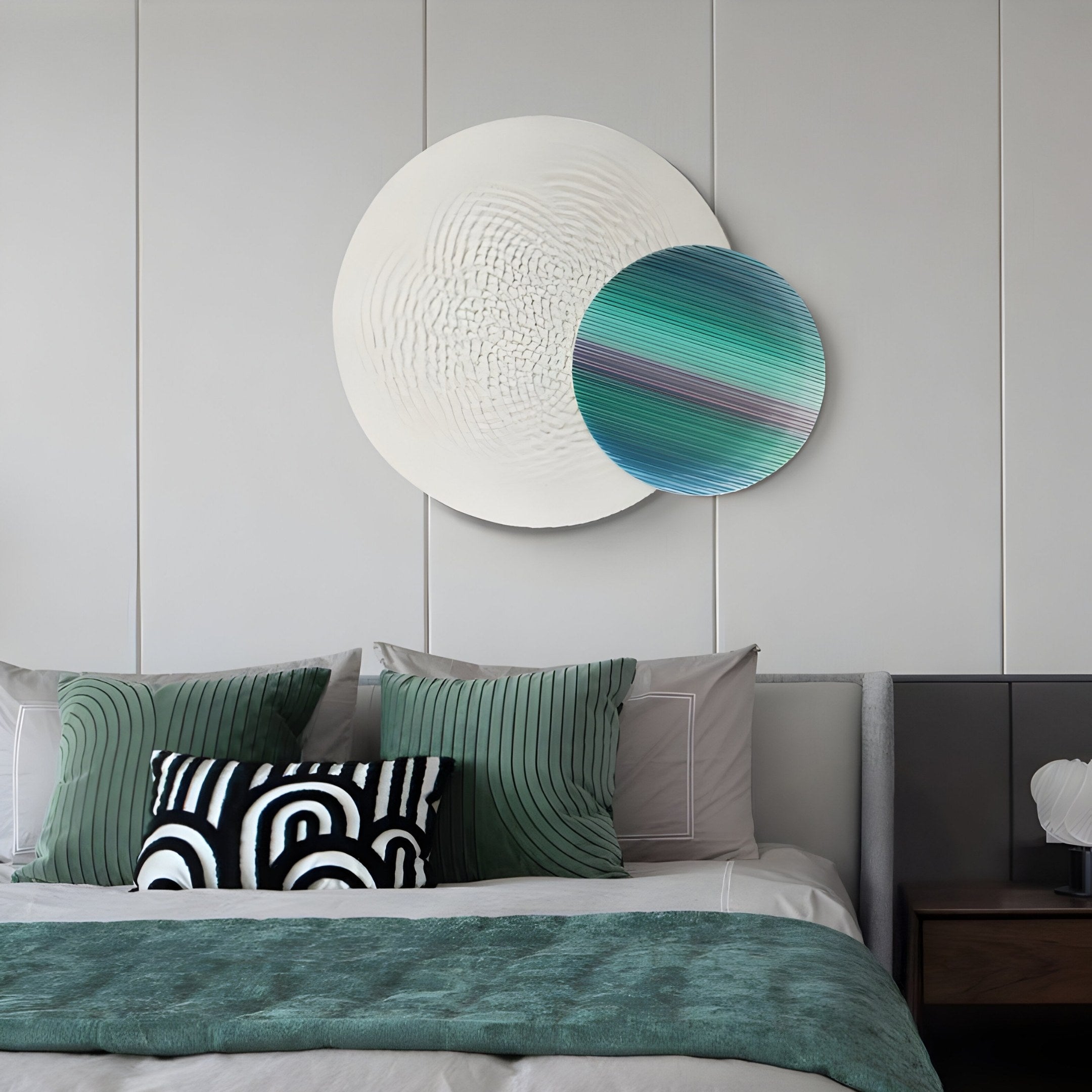 A modern bedroom features a bed with green and black bedding. The Lucentis White & Teal Gradient Wood Relief 3D Wall Art by Giant Sculptures enhances two concentric circles above the bed, creating an artistic focal point. A black and white patterned pillow adds contrast to the sleek aesthetic.