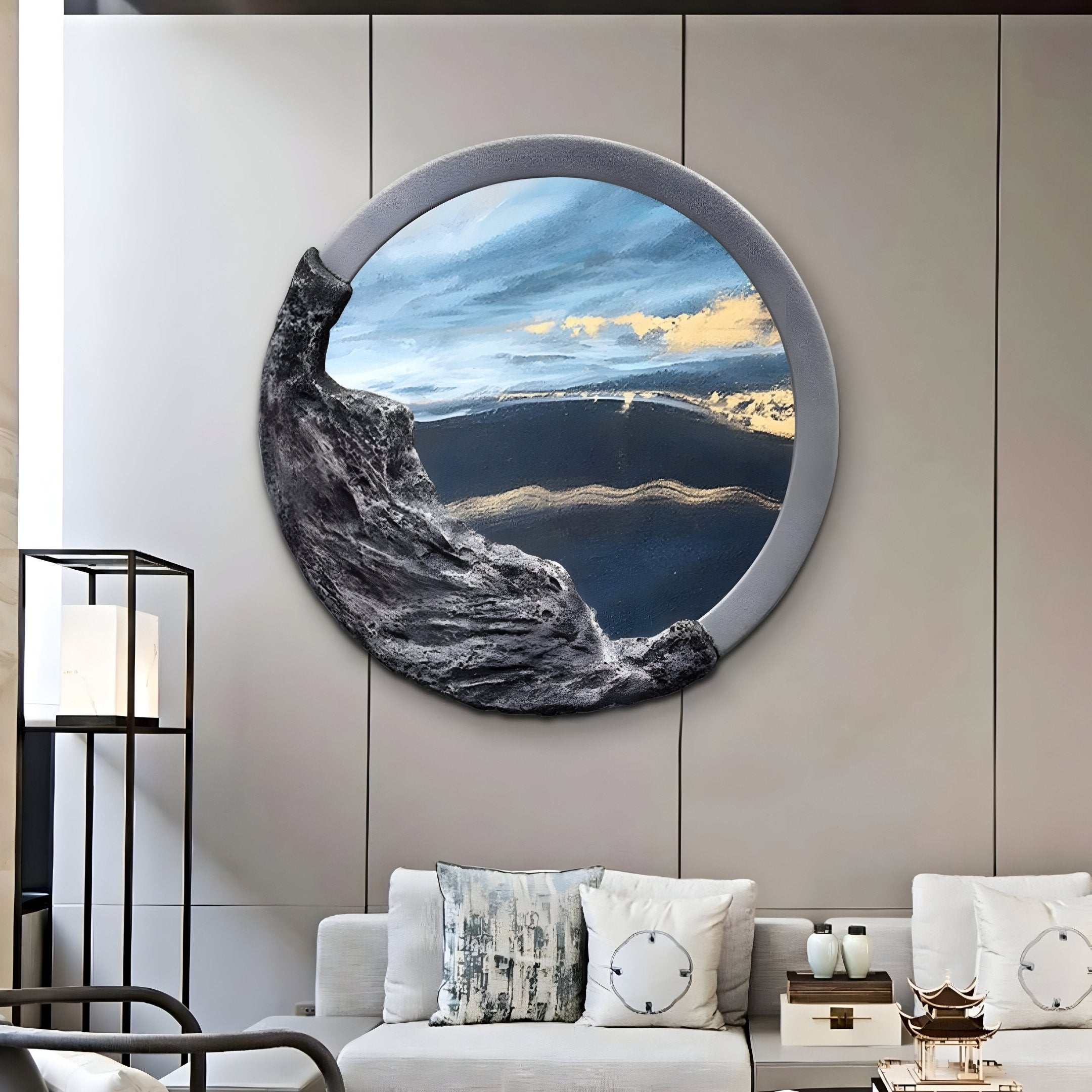 A modern living room featuring a white sofa, decorative cushions, and the Auroria Urban Mosaic Hand-Painted Wood Relief 3D Wall Art by Giant Sculptures. This piece evokes an abstract landscape with gray, black, and blue tones, showcasing textured rocky elements and metallic accents.