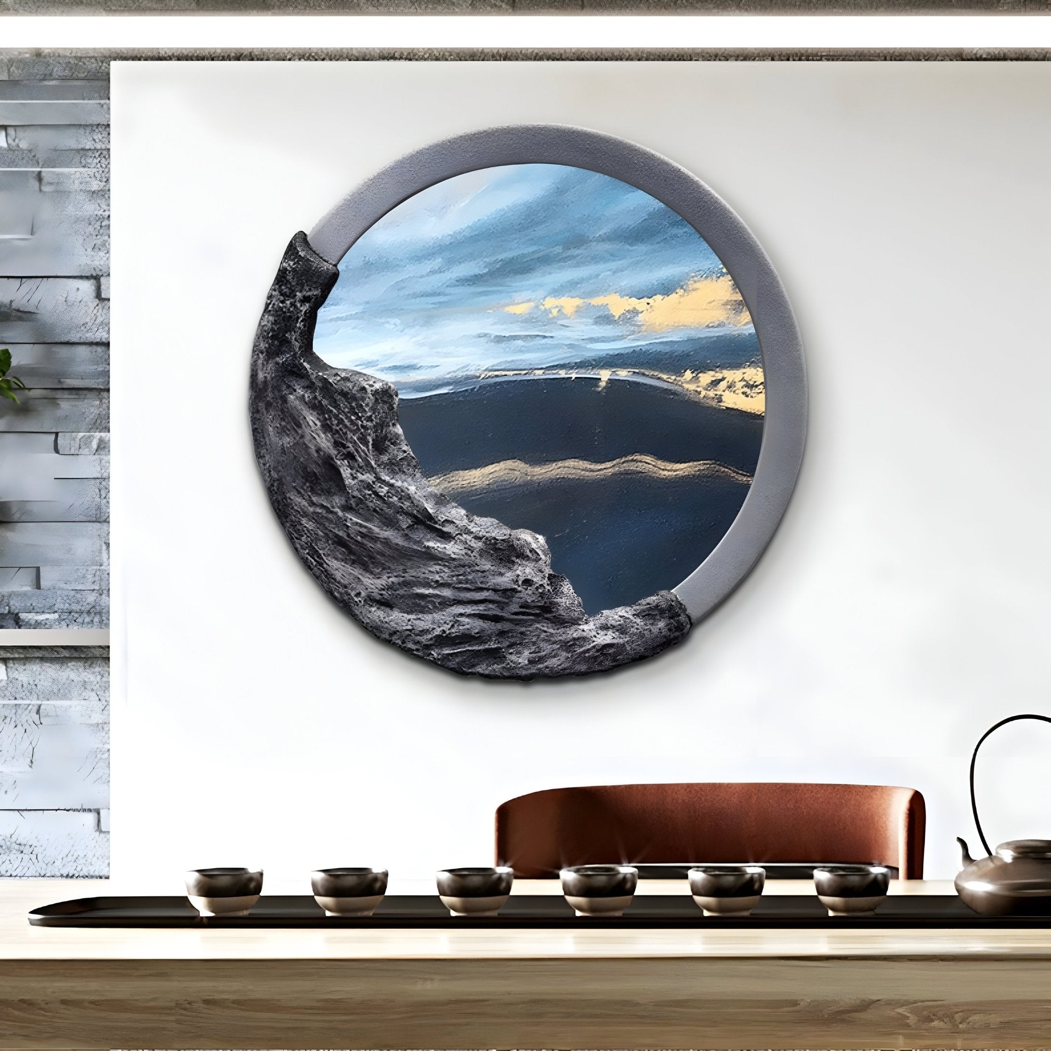 A modern art piece with a round frame from Giant Sculptures hangs on a white wall, showcasing the Auroria Urban Mosaic Hand-Painted Wood Relief 3D Wall Art blending sky and rocky landscape. Below, a wooden table with tea cups adds to the minimalist decor in front of the brown couch.