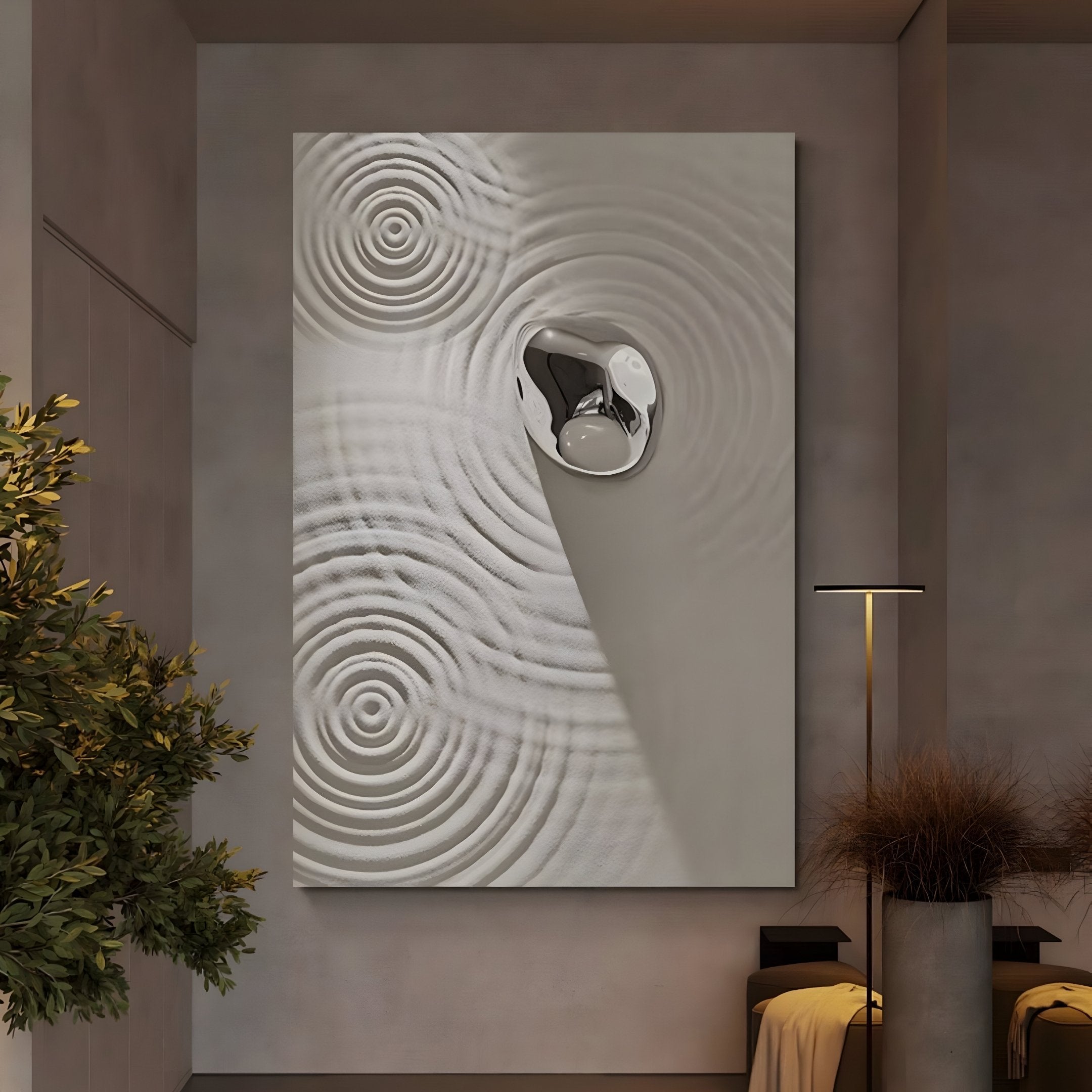 The Ondella Silver Ripple II Sandstone Wood Relief 3D Wall Art by Giant Sculptures features concentric circles and a central shiny, irregular metallic design. The minimalist room gains sophistication through its small lamp, foliage, and beige decor.