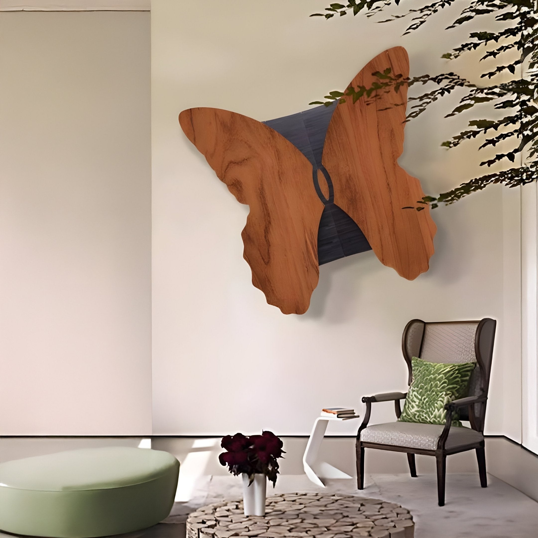The Lucerna Teak Butterfly Wood Carving 3D Wall Art by Giant Sculptures decorates a minimalist room. A chair with a green cushion and a small table holding a red flower vase sit on a circular textured rug. Nearby, you can see a low round ottoman while leaf shadows fall on the wall.