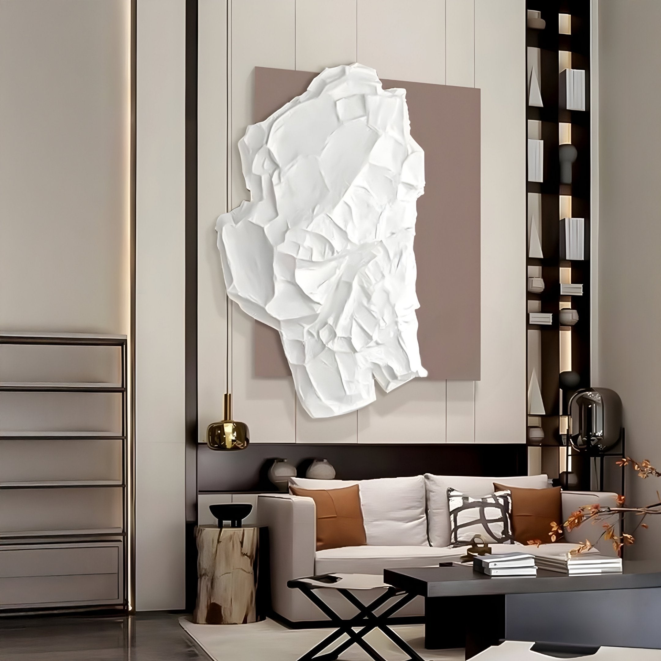 A modern living room boasts a white couch, black and white cushions, and a coffee table. A Veritas White & Taupe Wood Relief 3D Wall Art by Giant Sculptures is the centerpiece, accompanied by minimalist decor featuring a sleek black shelf and small wooden side table for an effortlessly chic ambiance.