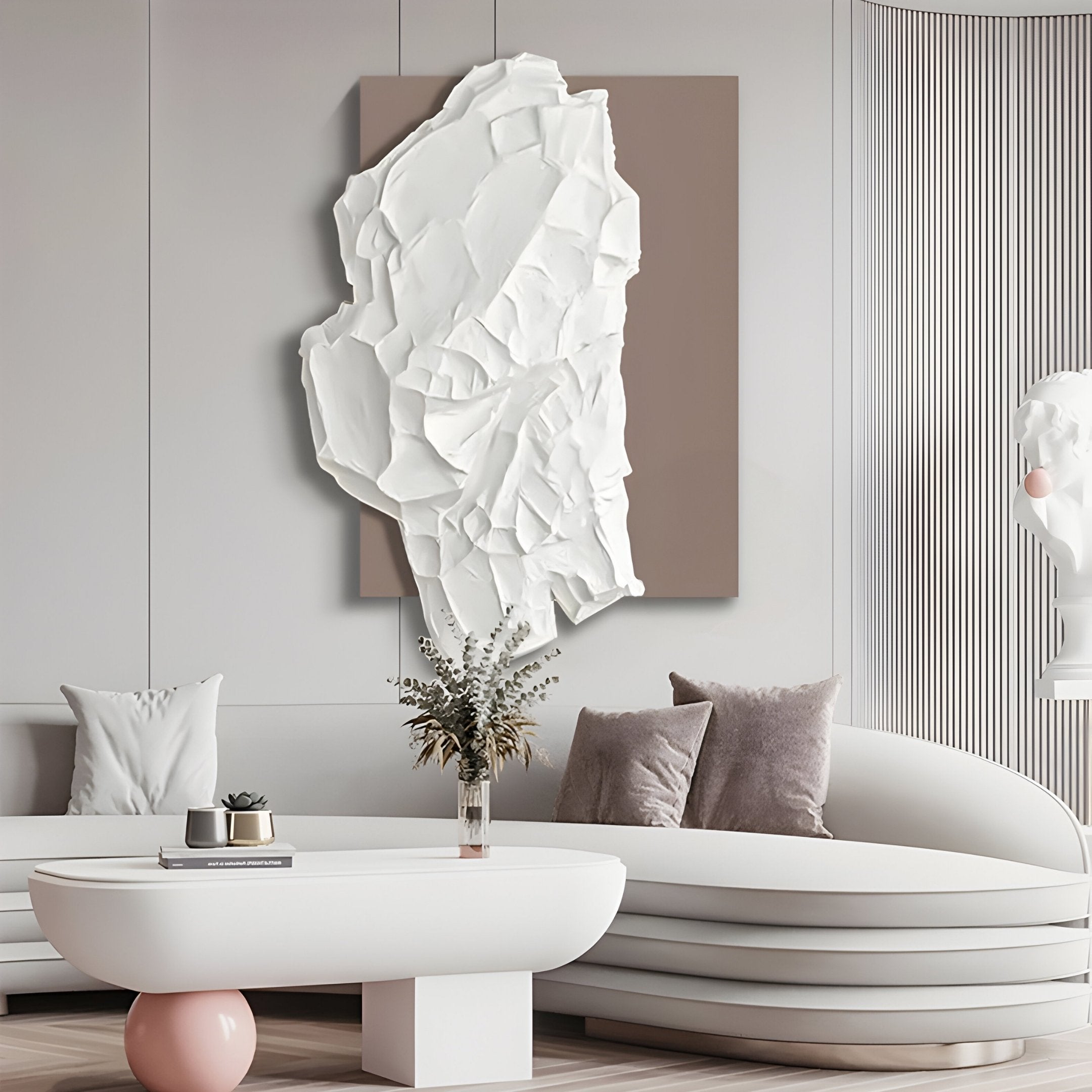 A modern living room exudes contemporary style with the Giant Sculptures Veritas White & Taupe Wood Relief 3D Wall Art, a large abstract sculpture on a beige panel. The space includes a curved white sofa, vases with dried flowers, and soft textured cushions for an inviting touch.