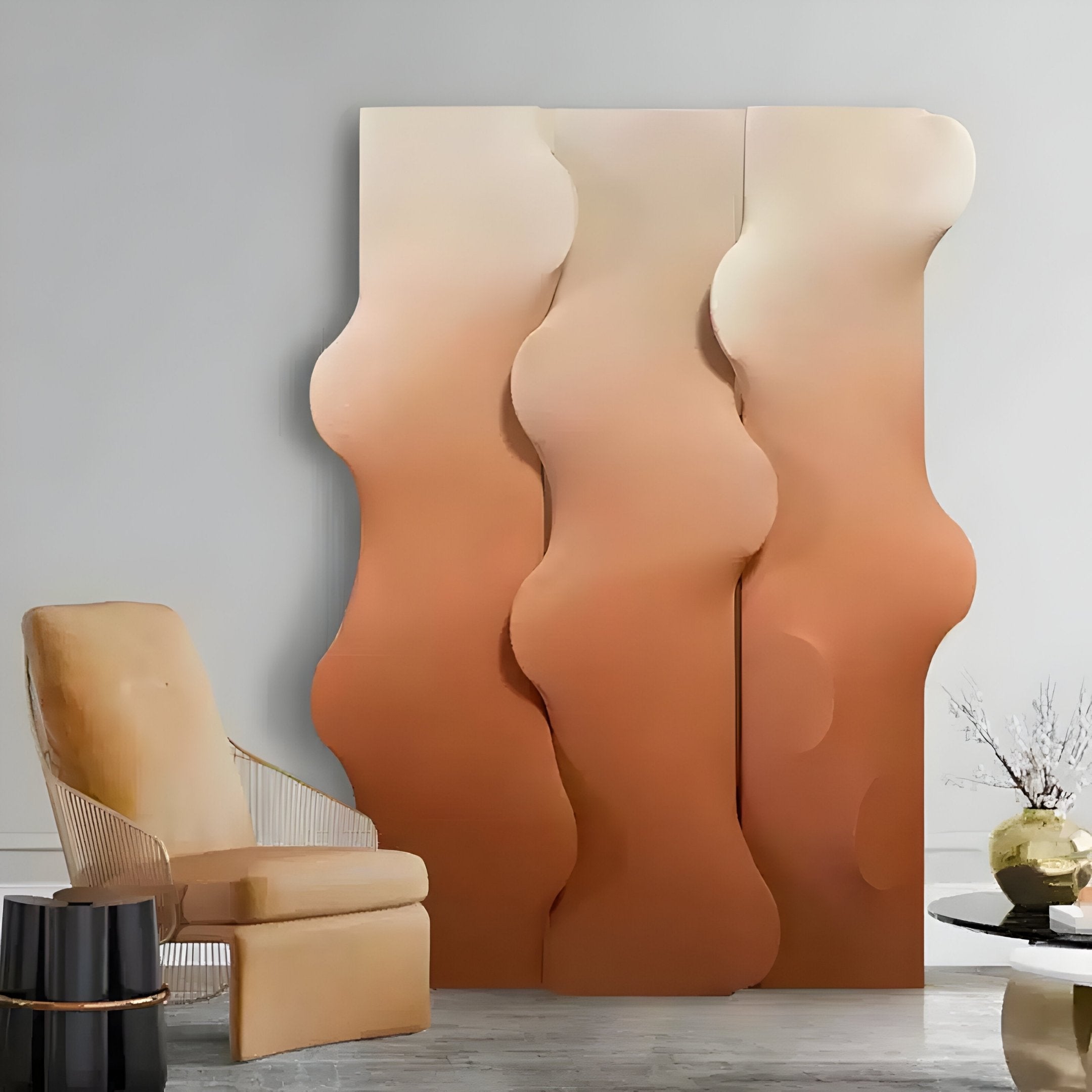 A modern interior features a wavy, gradient room divider in beige and brown. To the left, an elegant armchair with a light cushion complements the space, while a small round table with dried plants highlights contemporary decor using Giant Sculptures Mystique Orange Fabric Abstract Wood Relief 3D Wall Art.