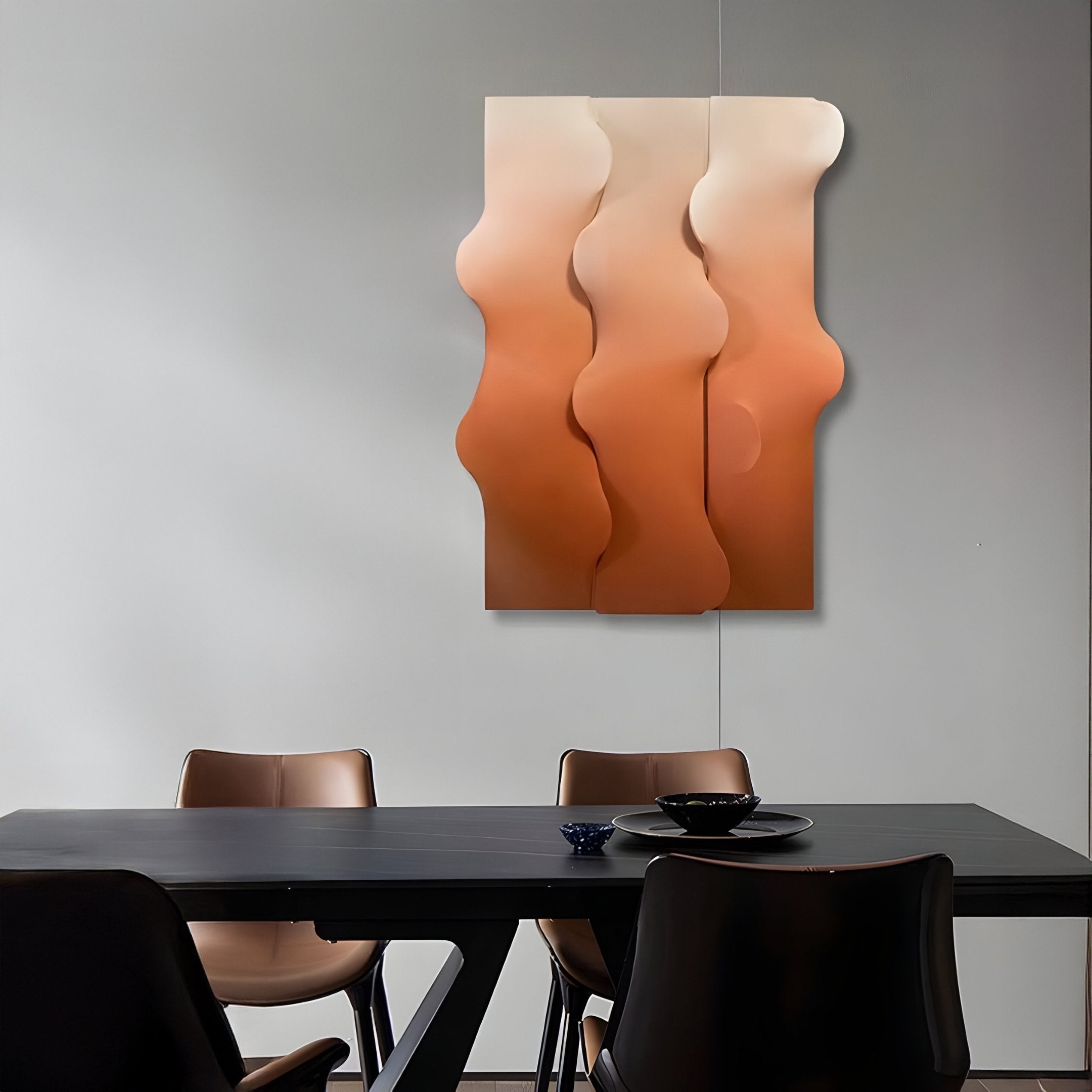 A modern dining room features a black table with brown chairs and is enhanced by the Mystique Orange Fabric Abstract Wood Relief 3D Wall Art from Giant Sculptures, showcasing wavy white and beige patterns. The minimalist design is accentuated by strategically placed dishes on the table.