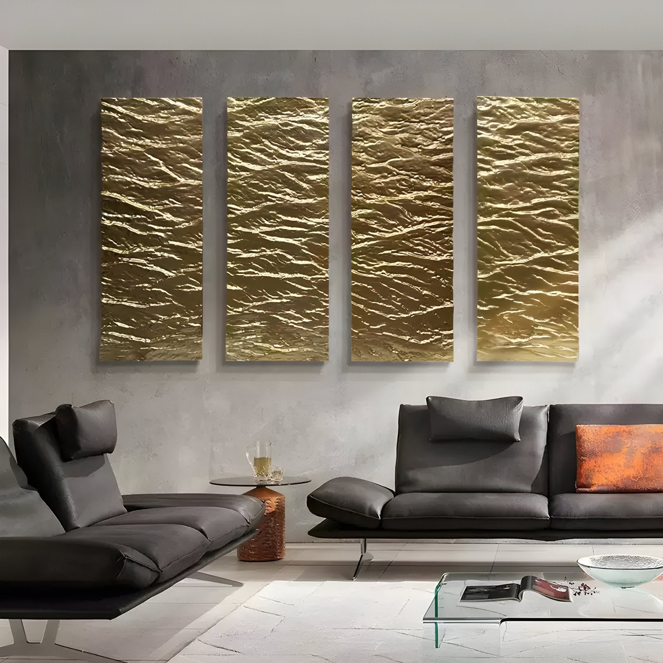 A modern living room boasts a gray sectional sofa and a glass coffee table, while four Illume 4-Panel Gold Hand-Painted Wood Relief 3D Wall Art pieces by Giant Sculptures adorn the concrete wall. A compact round side table with glasses and a decanter completes the minimalistic contemporary decor.