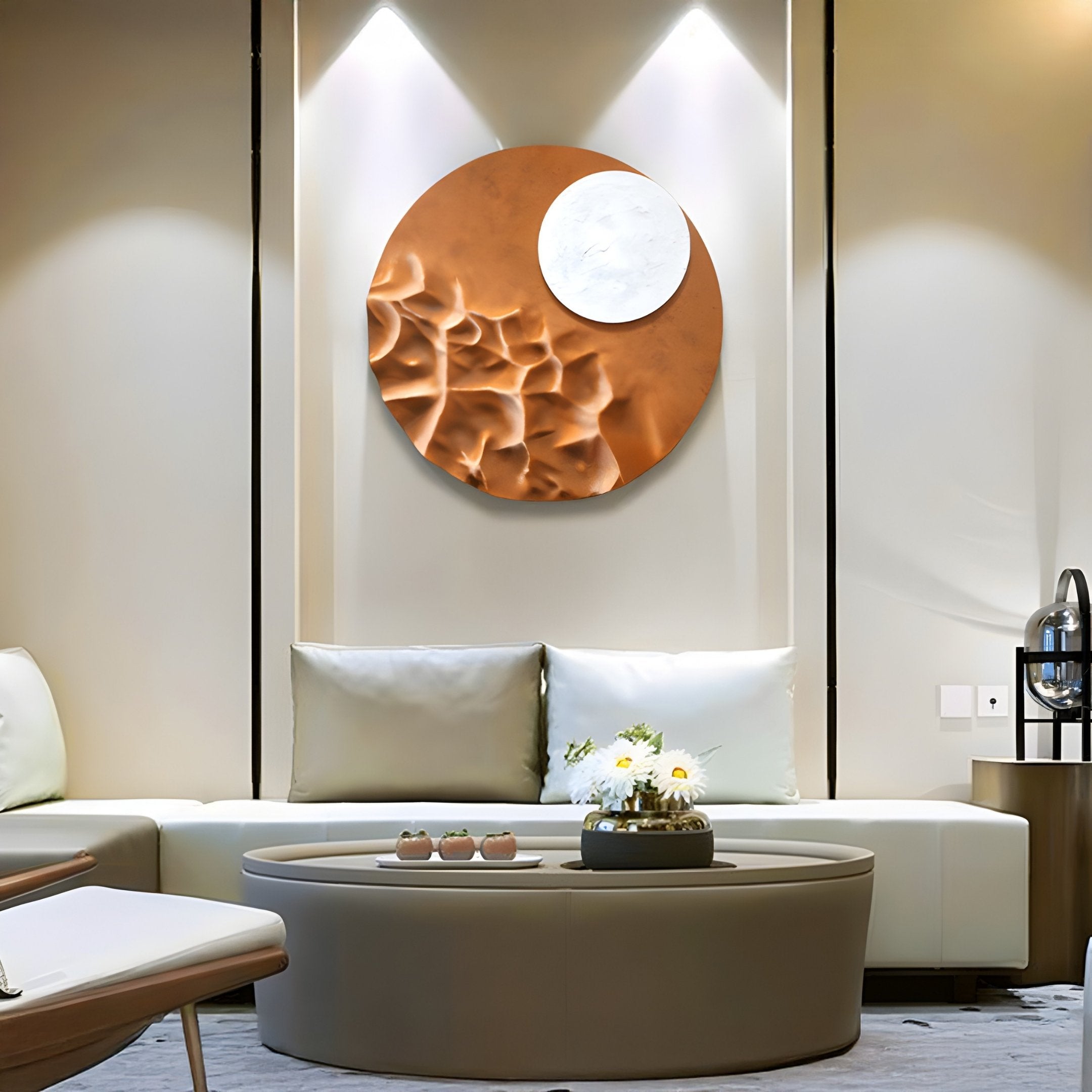 A modern living room features a circular coffee table and light-gray sofas. On the wall, an eye-catching Verve Earthy Brown Wood Relief 3D Wall Art by Giant Sculptures is illuminated by two small lamps. A vase of white flowers on the table highlights the contemporary design.