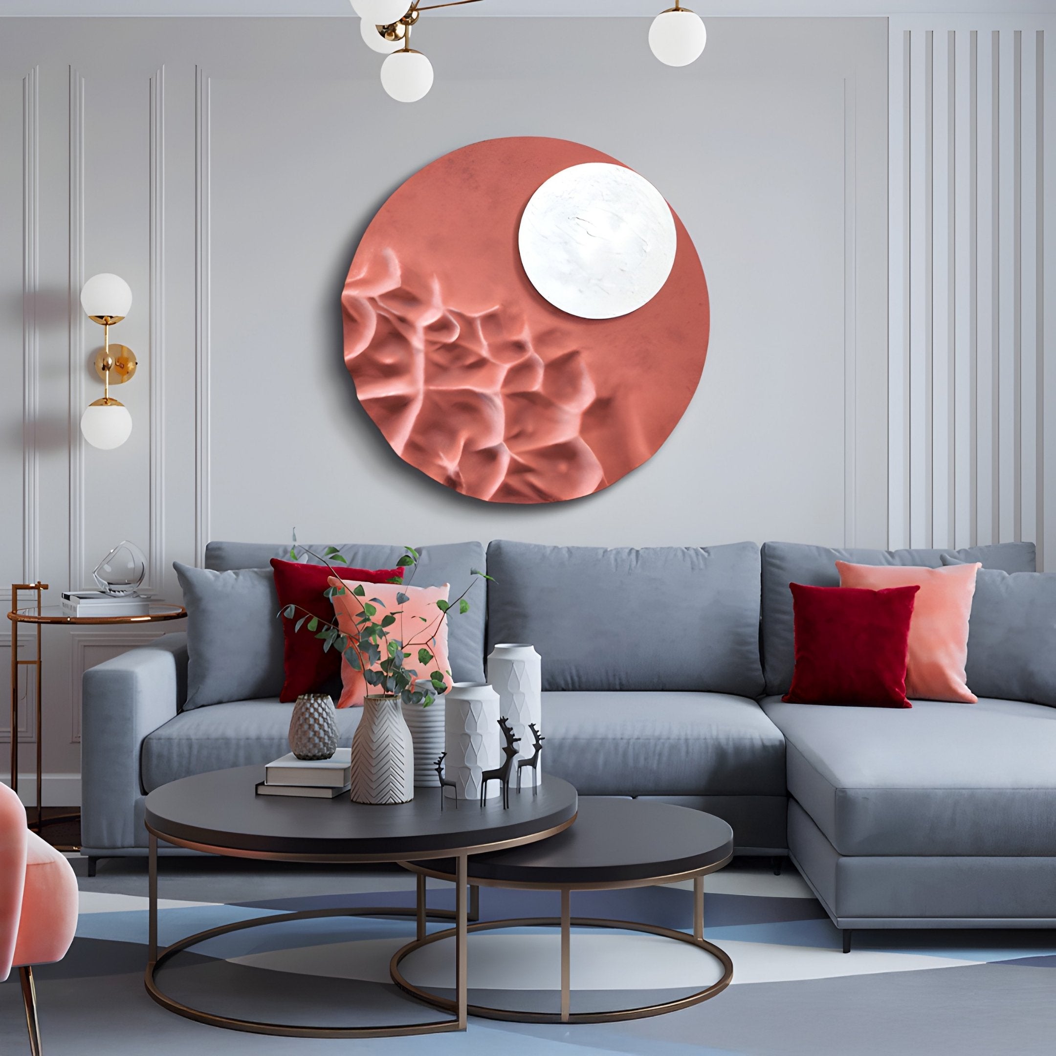 A modern living room features a gray sectional sofa accented by red and pink cushions. The gray wall is adorned with the Verve Dusty Rose Wood Relief 3D Wall Art by Giant Sculptures. Two round coffee tables, topped with decorative vases, and hanging globe lights add a contemporary touch.