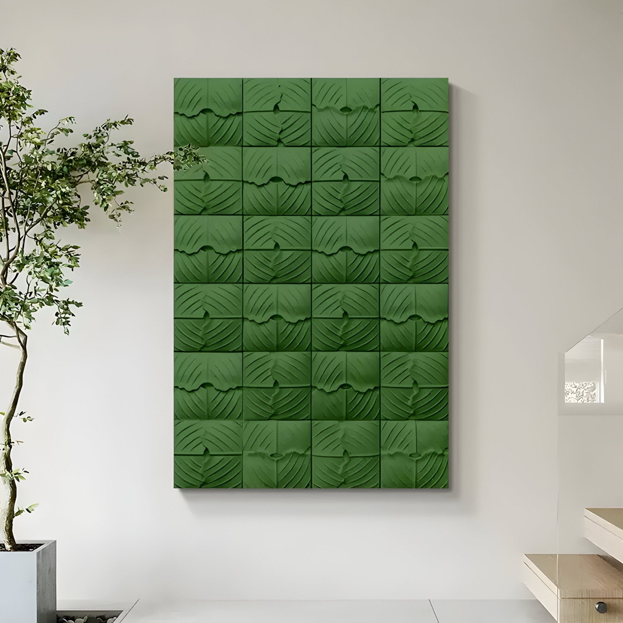 The Vellura Green Textured Wood Relief 3D Wall Art by Giant Sculptures, featuring a geometric leaf pattern, hangs on a light wall near a potted plant and glass steps in a modern, minimalist interior.