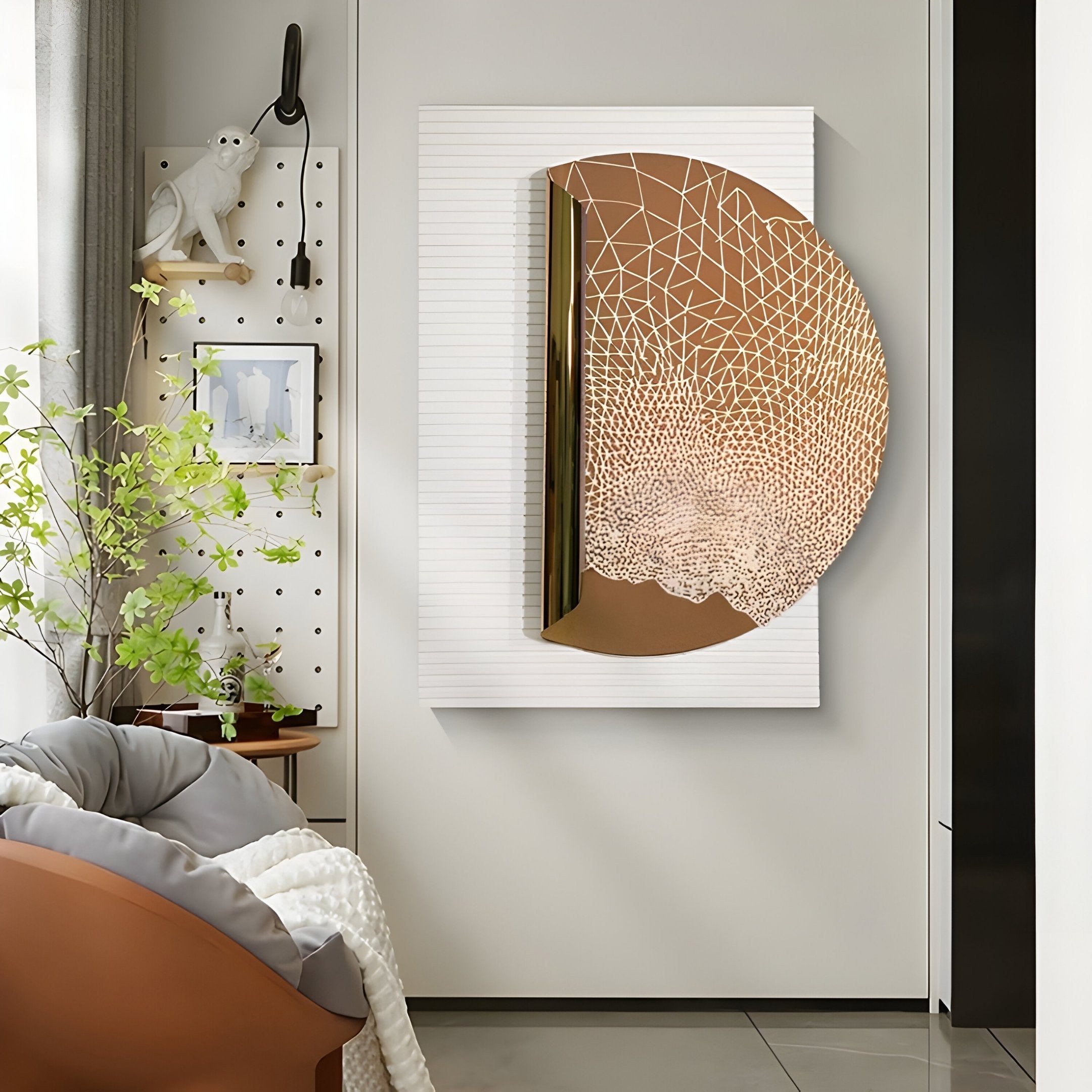 A modern living room featuring the Artevia Gold & White Geometric Wood Relief 3D Wall Art by Giant Sculptures, a small plant on a table, a cozy gray chair with a throw, and artistic décor including a white monkey sculpture on a pegboard.