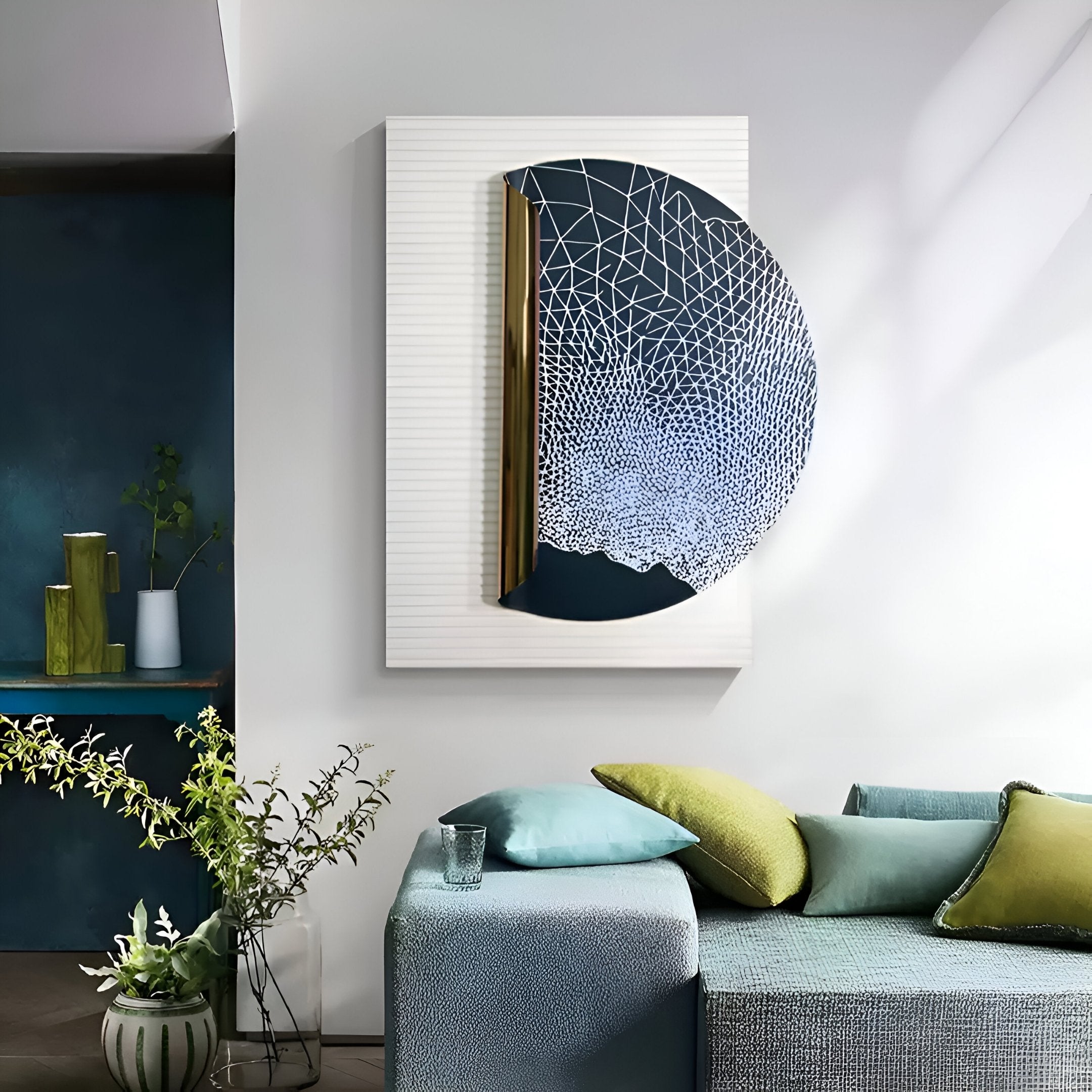 A modern living space with a gray-blue sofa, green and blue cushions, a small glass of water, and a plant. The wall showcases Giant Sculptures’ Artevia Blue & White Geometric Wood Relief 3D Wall Art with gold accents.