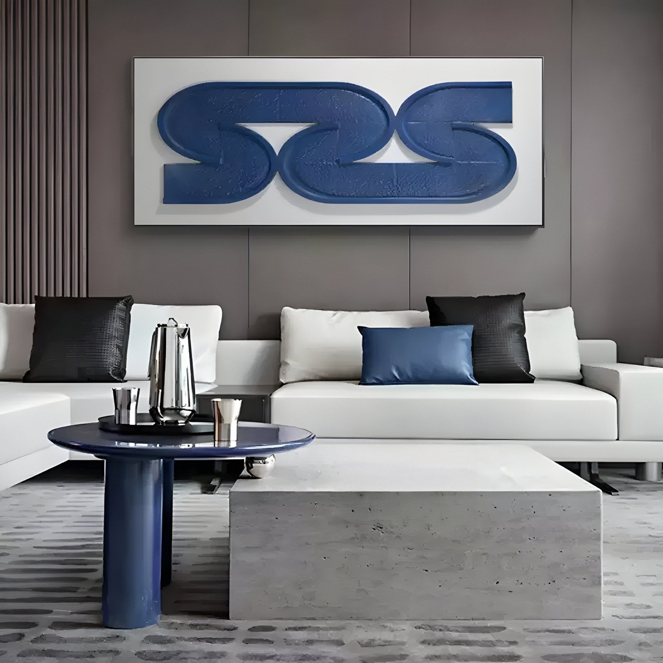 A modern living room features a white sectional sofa with black and blue cushions on a gray textured carpet. In the foreground are a round blue table and light gray coffee table. Behind the sofa, Giant Sculptures Infinique 3D Wall Art showcases horizontal blue abstract wood carving.