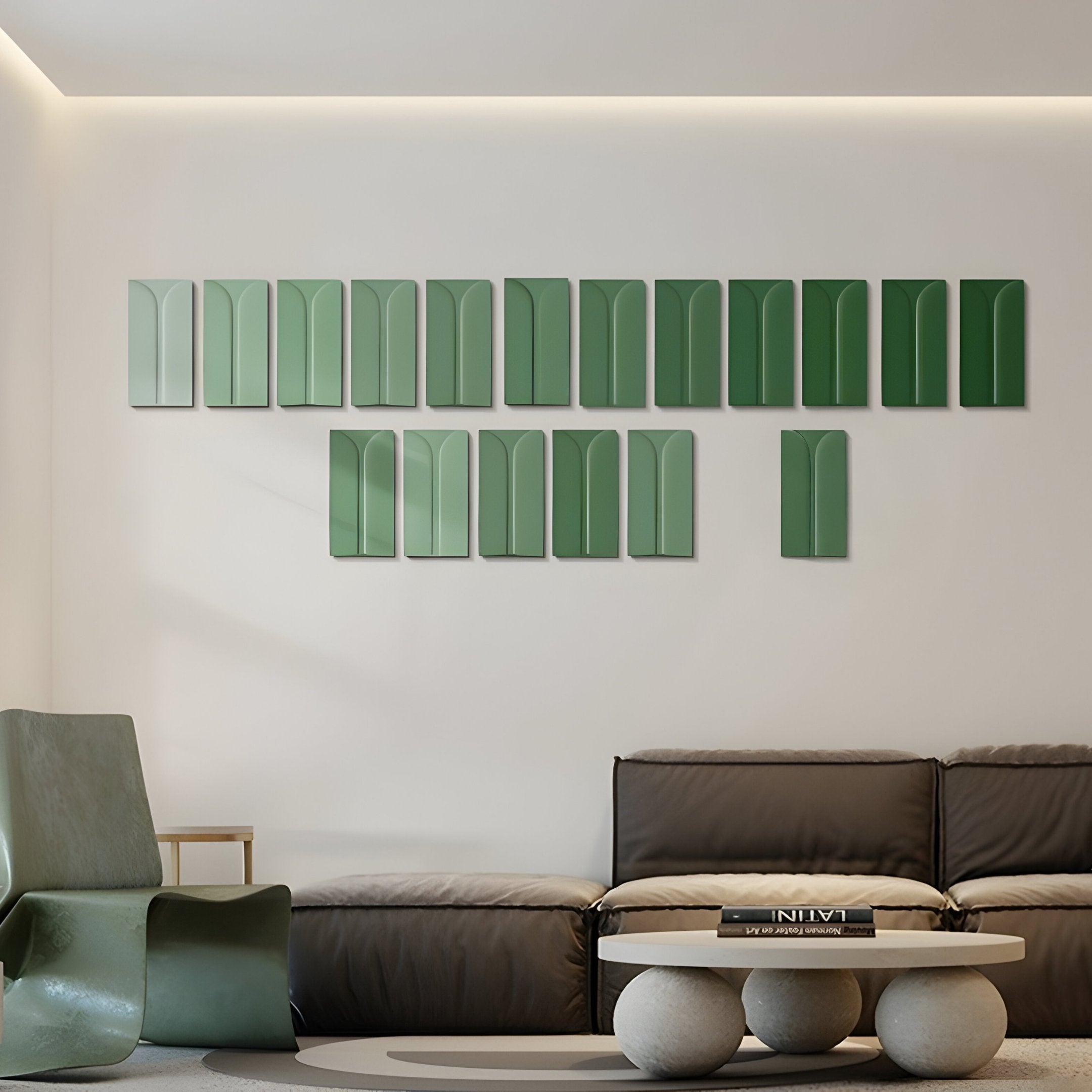 A modern living room features the Eximia Green Tones Multi-Panel Wood Relief 3D Wall Art by Giant Sculptures above a dark sofa. A minimalist coffee table with stacked books sits in front, while a uniquely shaped green chair complements the neutral-toned walls and floor.