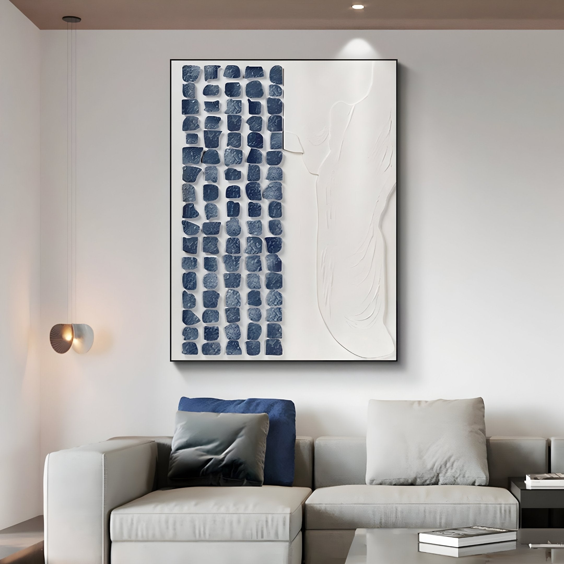 A contemporary living room showcases a gray sectional sofa paired with the Aestilis Blue & White Mosaic Wood Carving 3D Wall Art by Giant Sculptures. Modern lighting enhances the space, highlighting intricate textures and adding depth to the artworks vibrant hues.