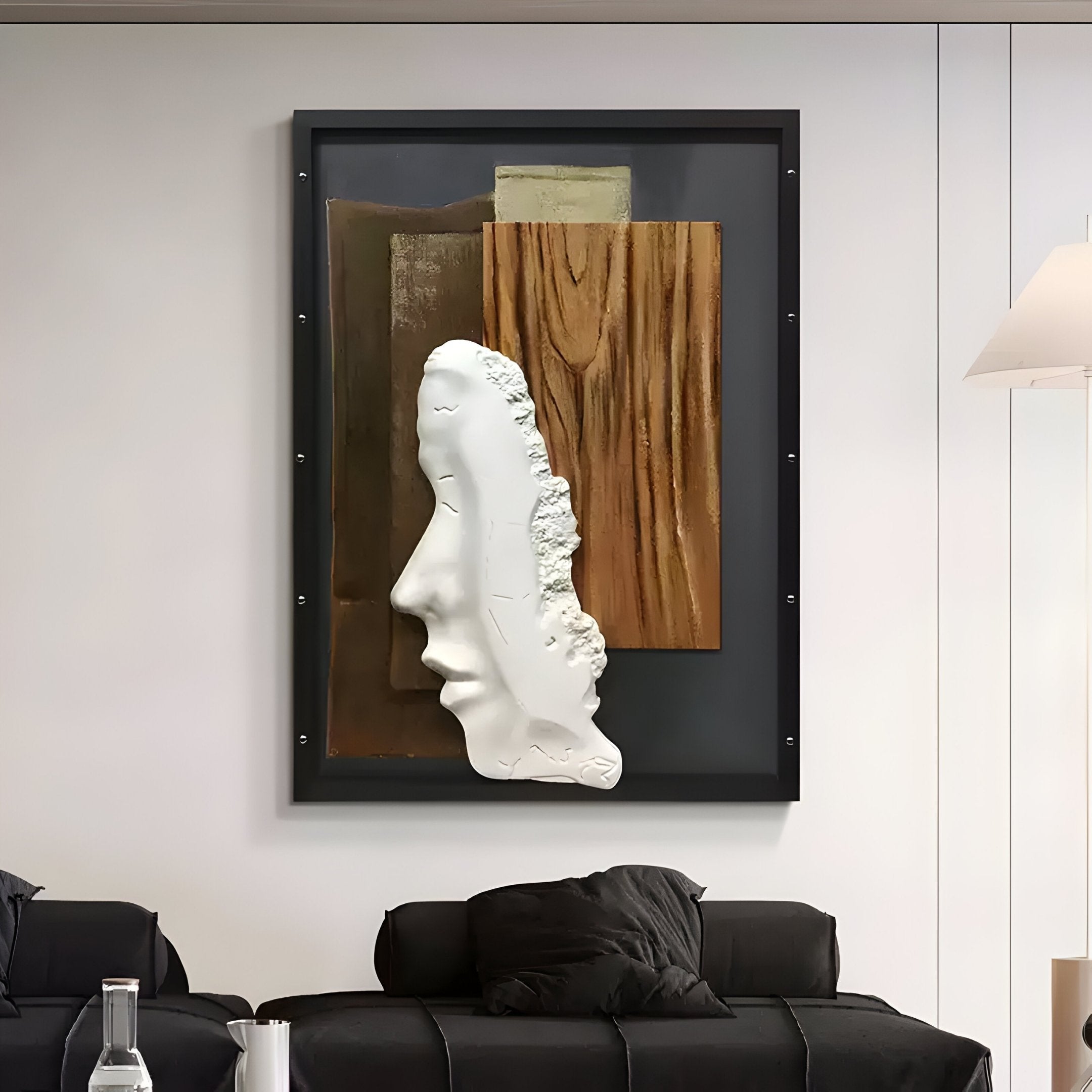 A modern living room features the Visagio Hand-Painted Wood Relief 3D Wall Art by Giant Sculptures, showcasing a sculpted side profile framed in black against Wabi-Sabi-inspired brown and beige panels, with a black couch and dark cushions adding to the serene look.