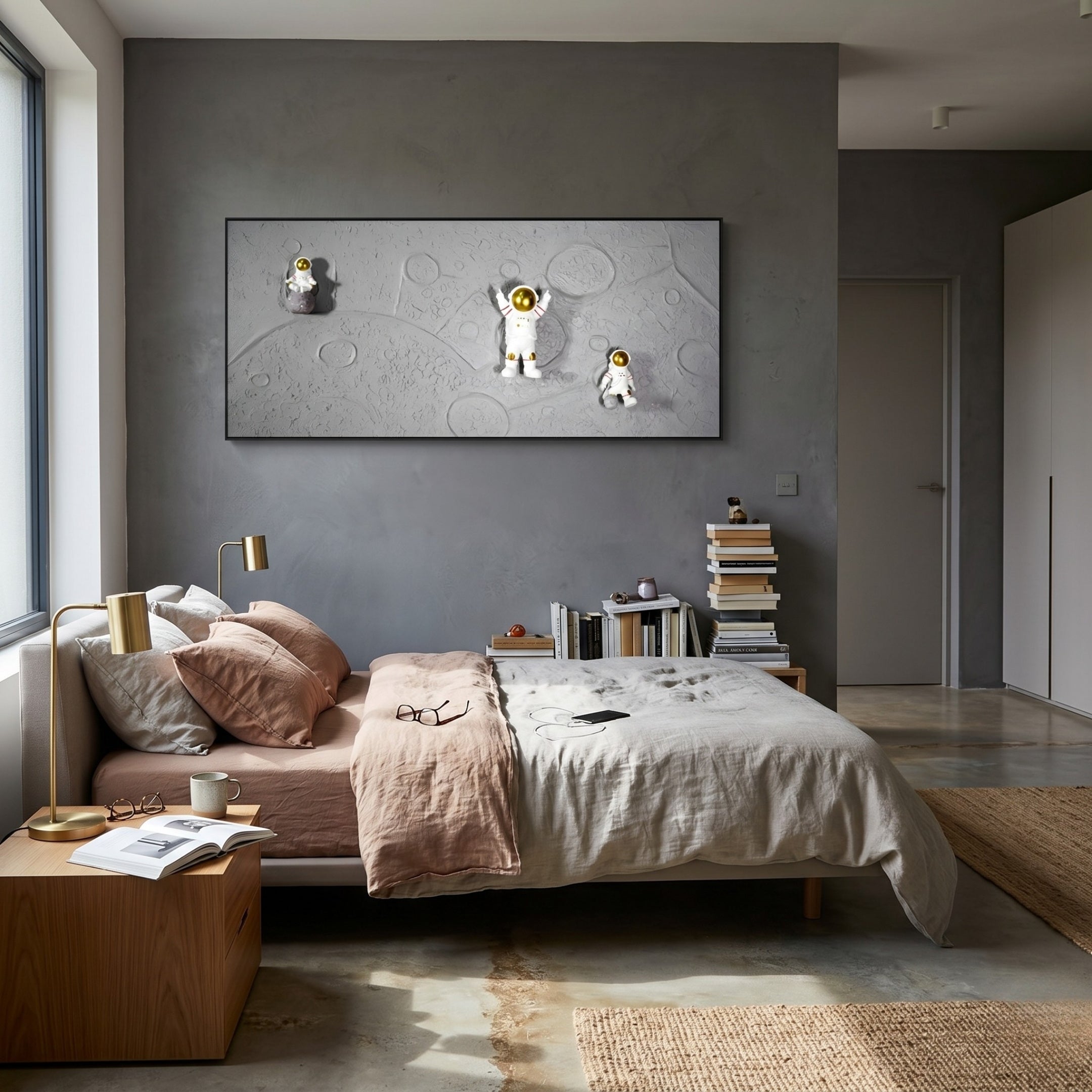 Modern bedroom with a neatly made bed, beige and pink bedding, books by the bed, gold lamps, and Giant Sculptures’ Astravera Lunar Crew Grey Textured Astronaut 3D Wall Art—showcasing three astronauts on a moon-like background.