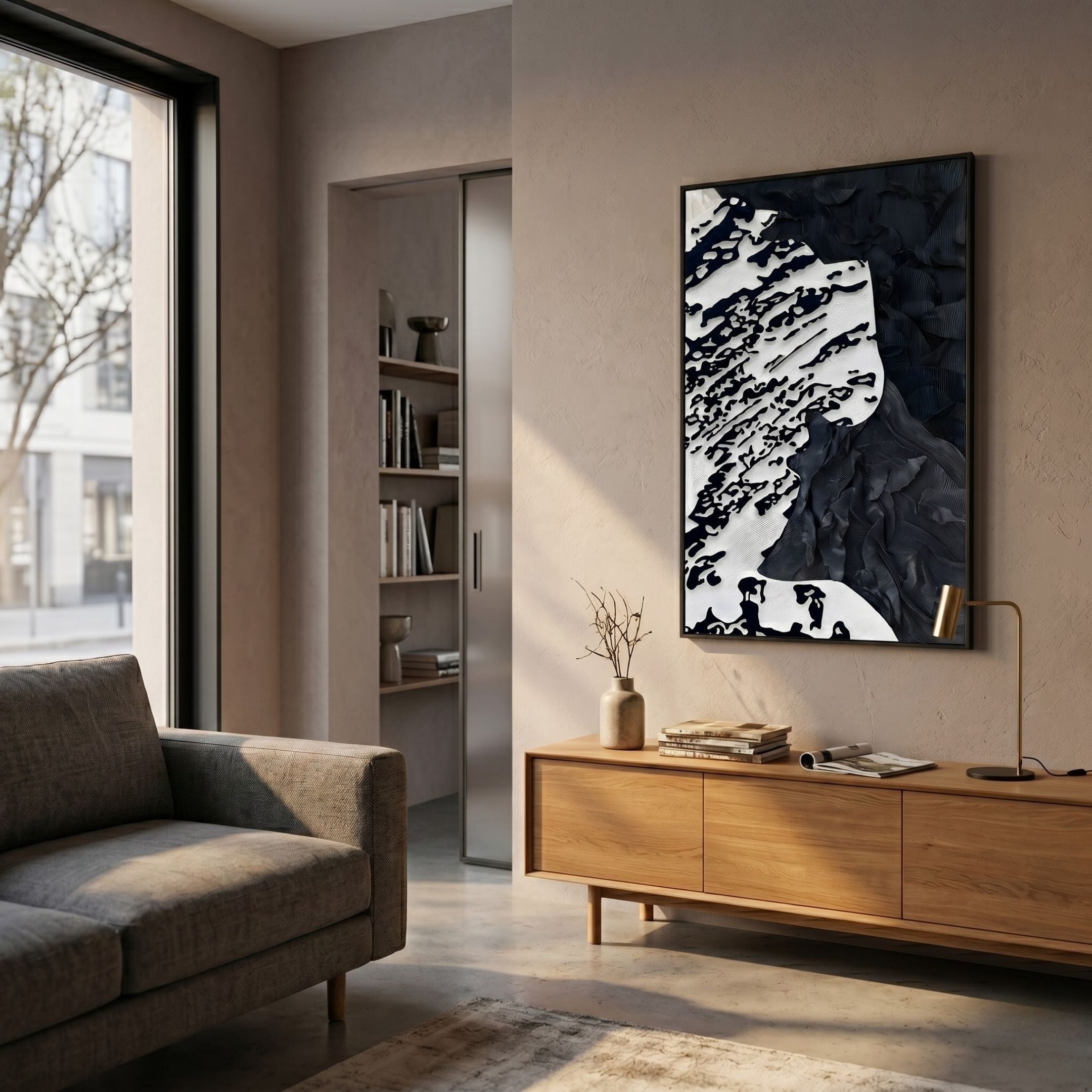 A modern living room with a gray sofa, wooden sideboard, and Giant Sculptures' Nivoria I Black & White Textured Abstract 3D Wall Art on the wall. Sunlight streams in as a small vase with branches sits atop the sideboard.