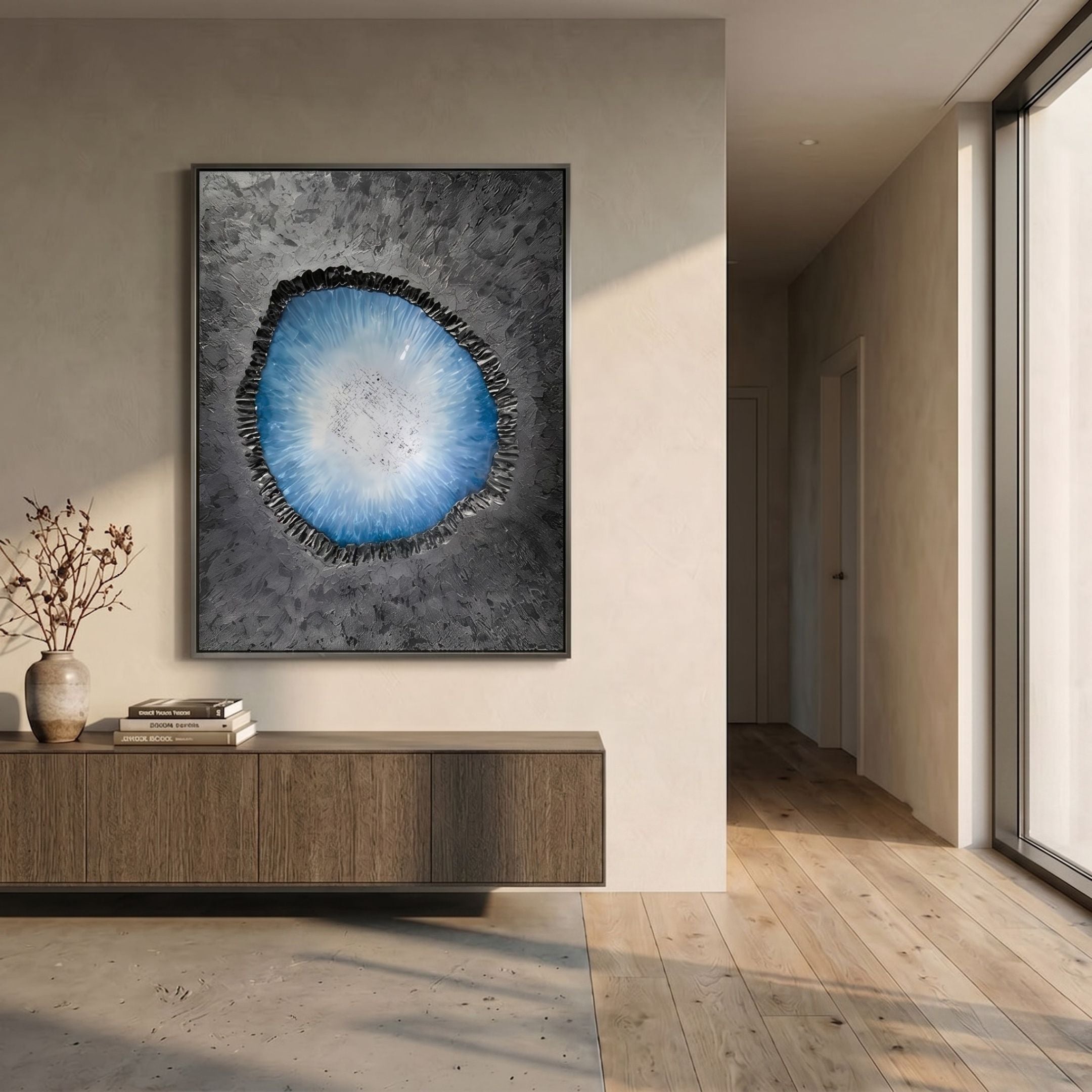 Vorthera Sky Radiance Textured Silver 3D Wall Art with a blue-white radiant disc and jagged black border, mounted above a wooden console in a sunlit hallway.