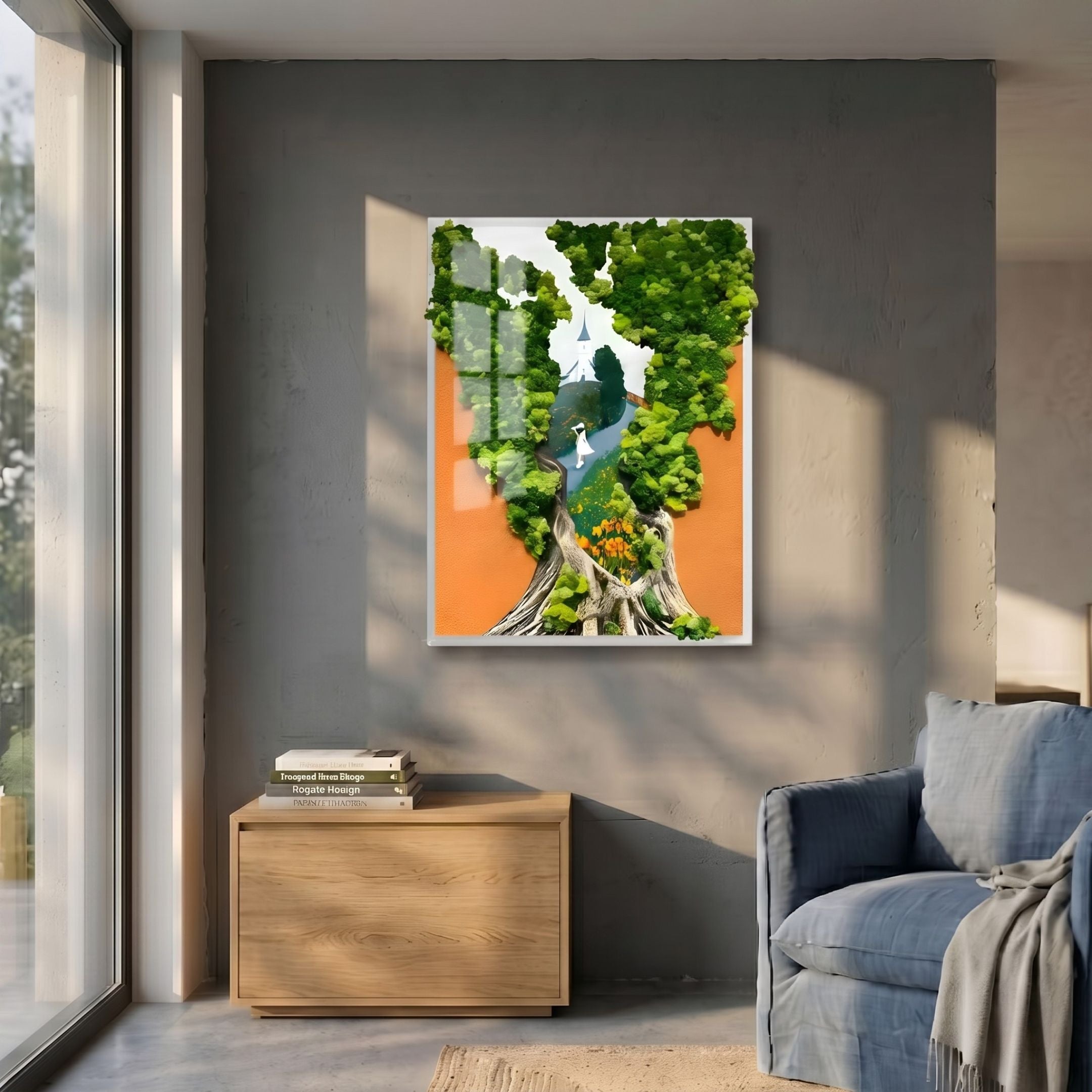Truvira Chapel Path Moss Framed 3D Wall Art by Giant Sculptures, featuring a green moss tree and white chapel on orange, displayed above a wooden cabinet beside a blue armchair.