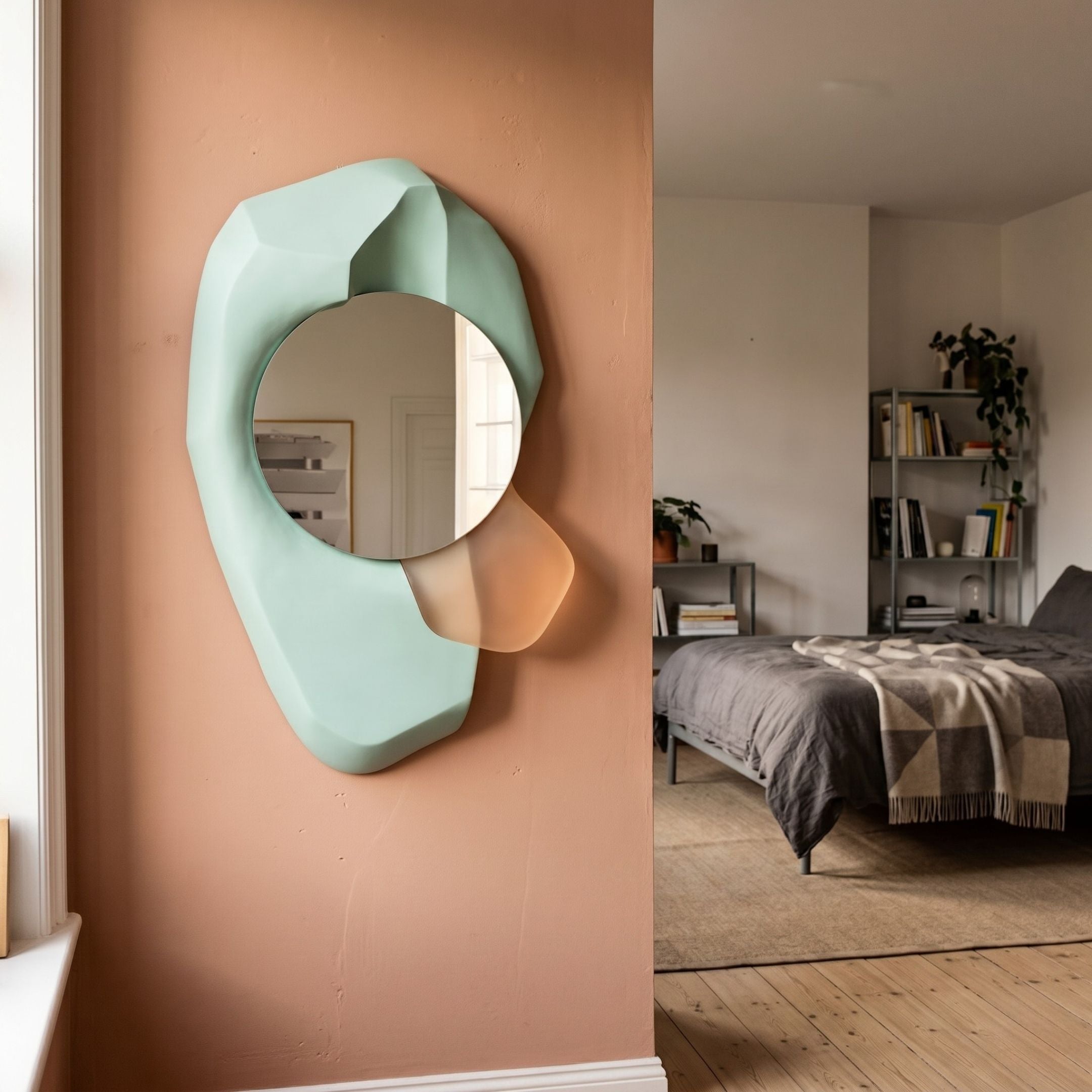 Ravira Aqua & Peach Sculptural Acrylic Mirror by Giant Sculptures mounted on a terracotta hallway wall beside a bedroom with grey bedding and shelving.