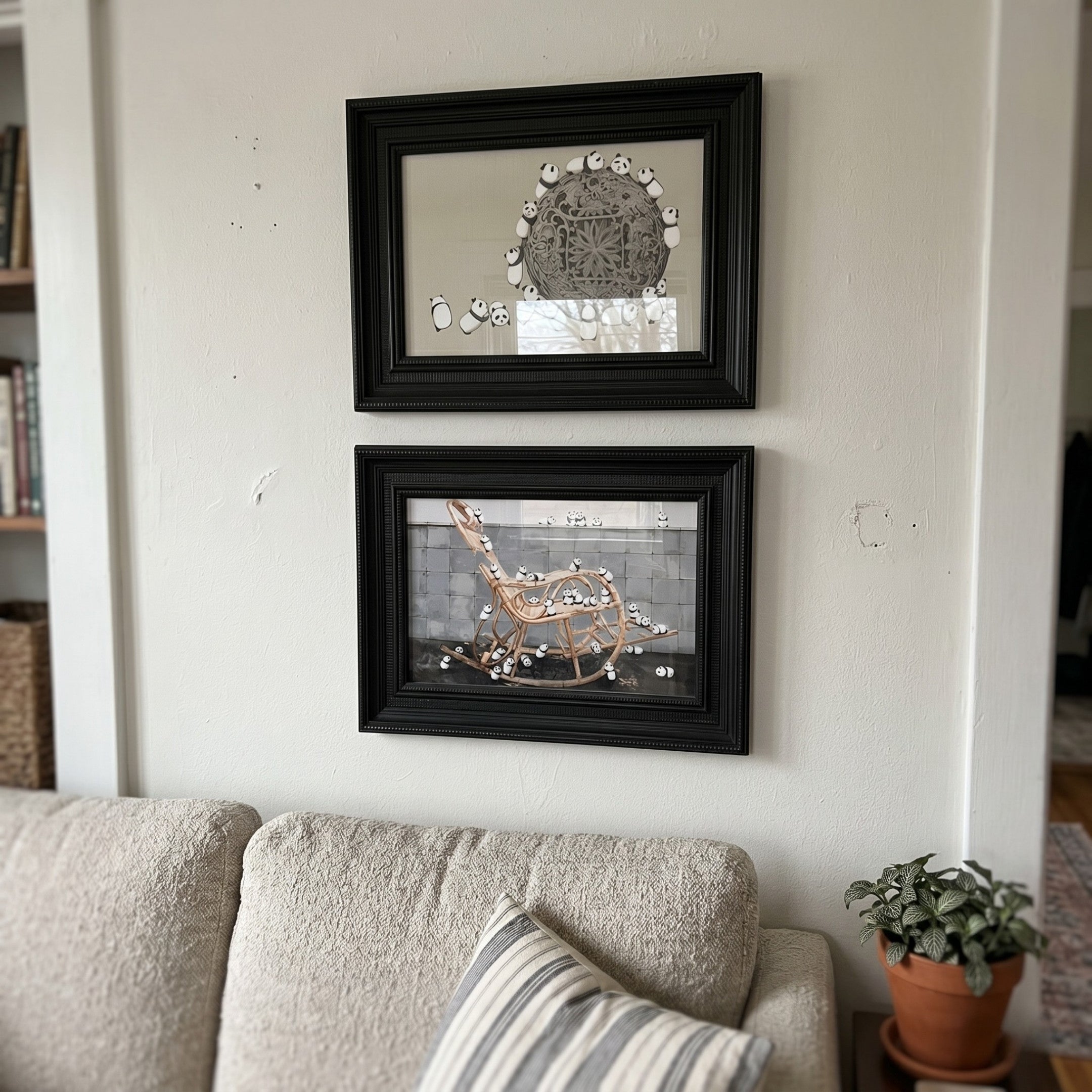 Ardensir Panda Play Illustration 2-Set Framed Wall Art by Giant Sculptures displayed stacked on a cream wall above a beige sofa, featuring black wood frames with panda-covered sphere and rocking chair scenes.
