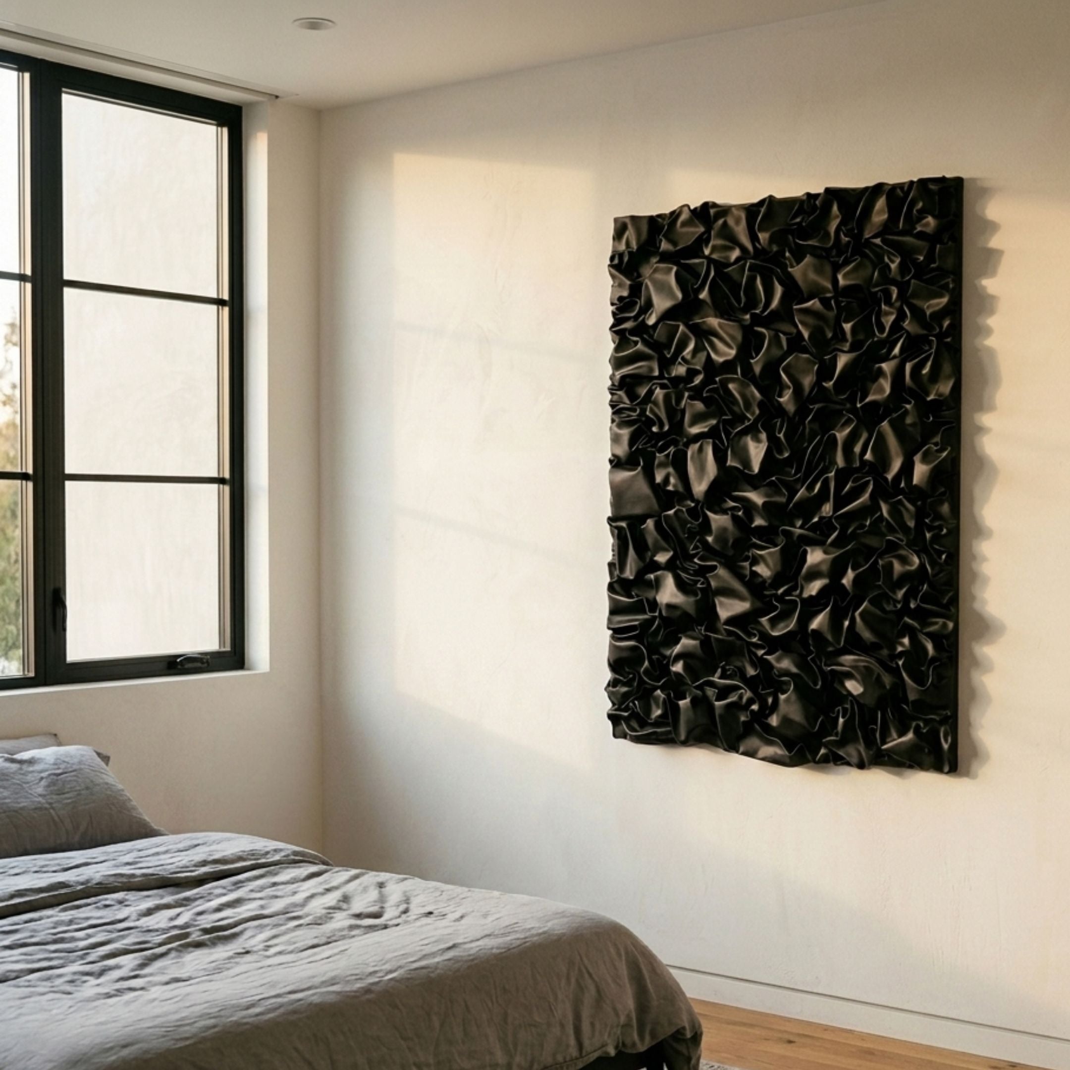 Veltrix Black Folded Leather 3D Wall Art by Giant Sculptures mounted on a cream bedroom wall beside a black-framed window and a grey linen bed.