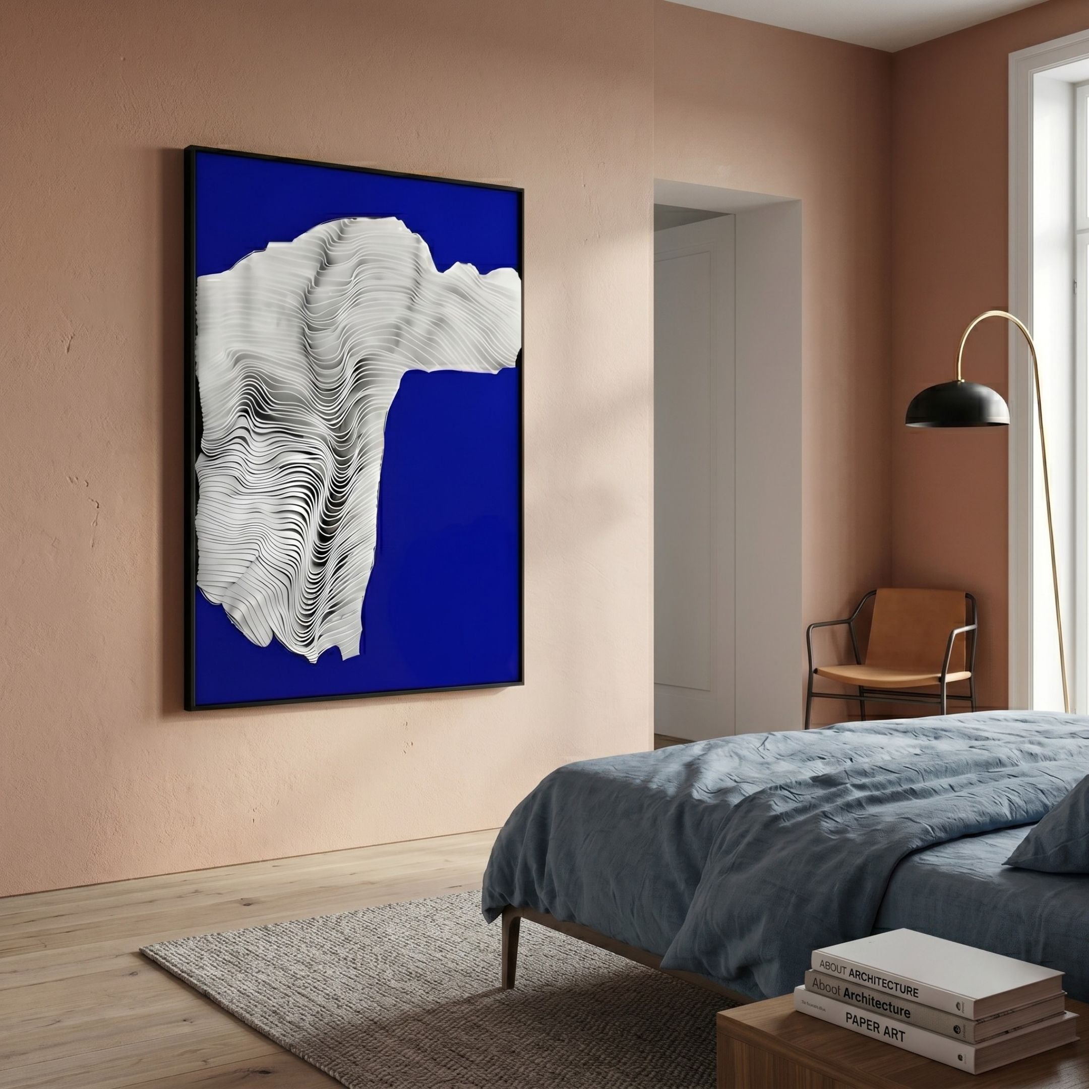 Ravelle Cobalt Contour Felt 3D Relief Wall Art with layered white wavy forms on cobalt blue, framed on a peach bedroom wall above a blue-linen bed.