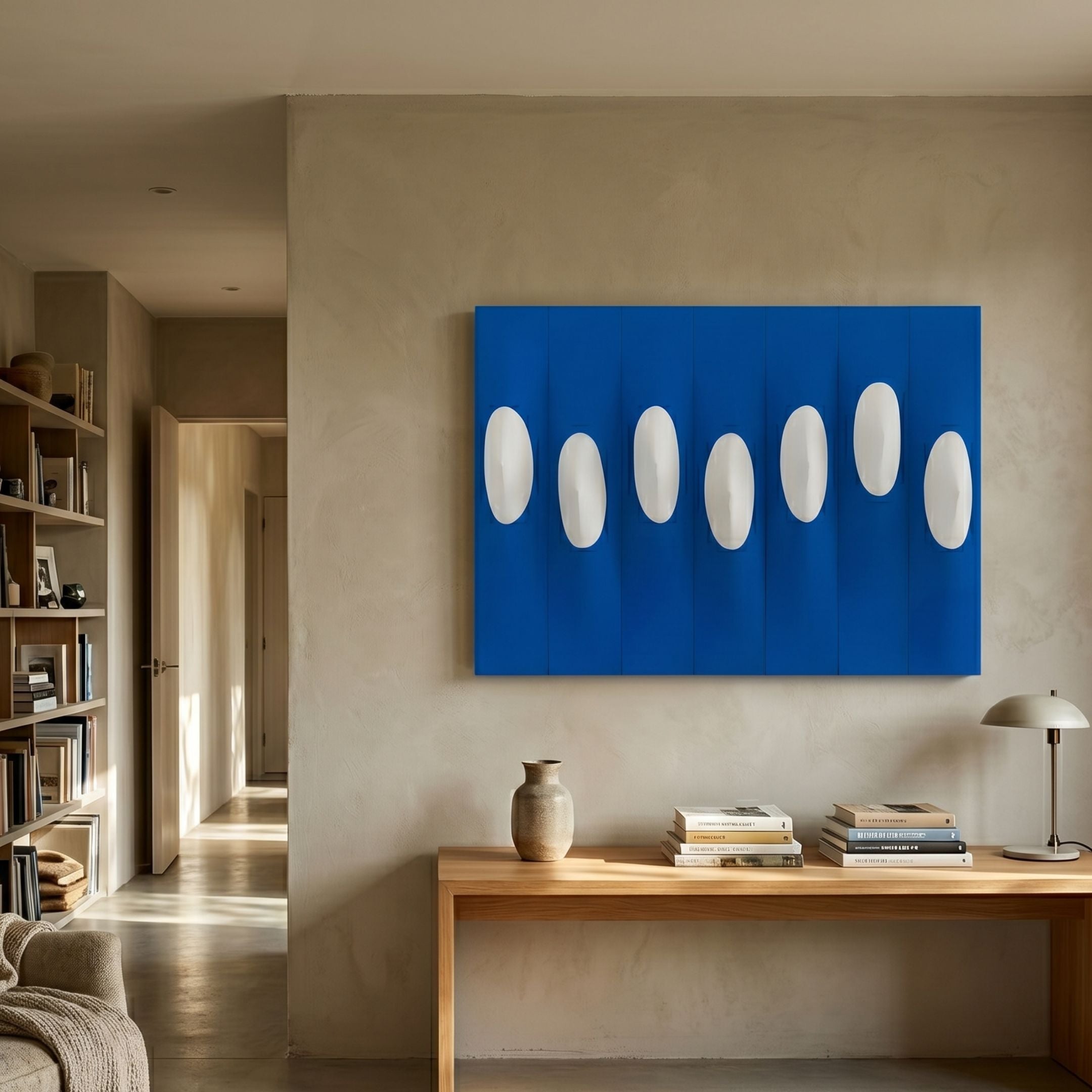 Virello Royal Blue & White Disc Leather 3D Wall Art by Giant Sculptures displayed above a wooden console table in a neutral living room with bookshelves.