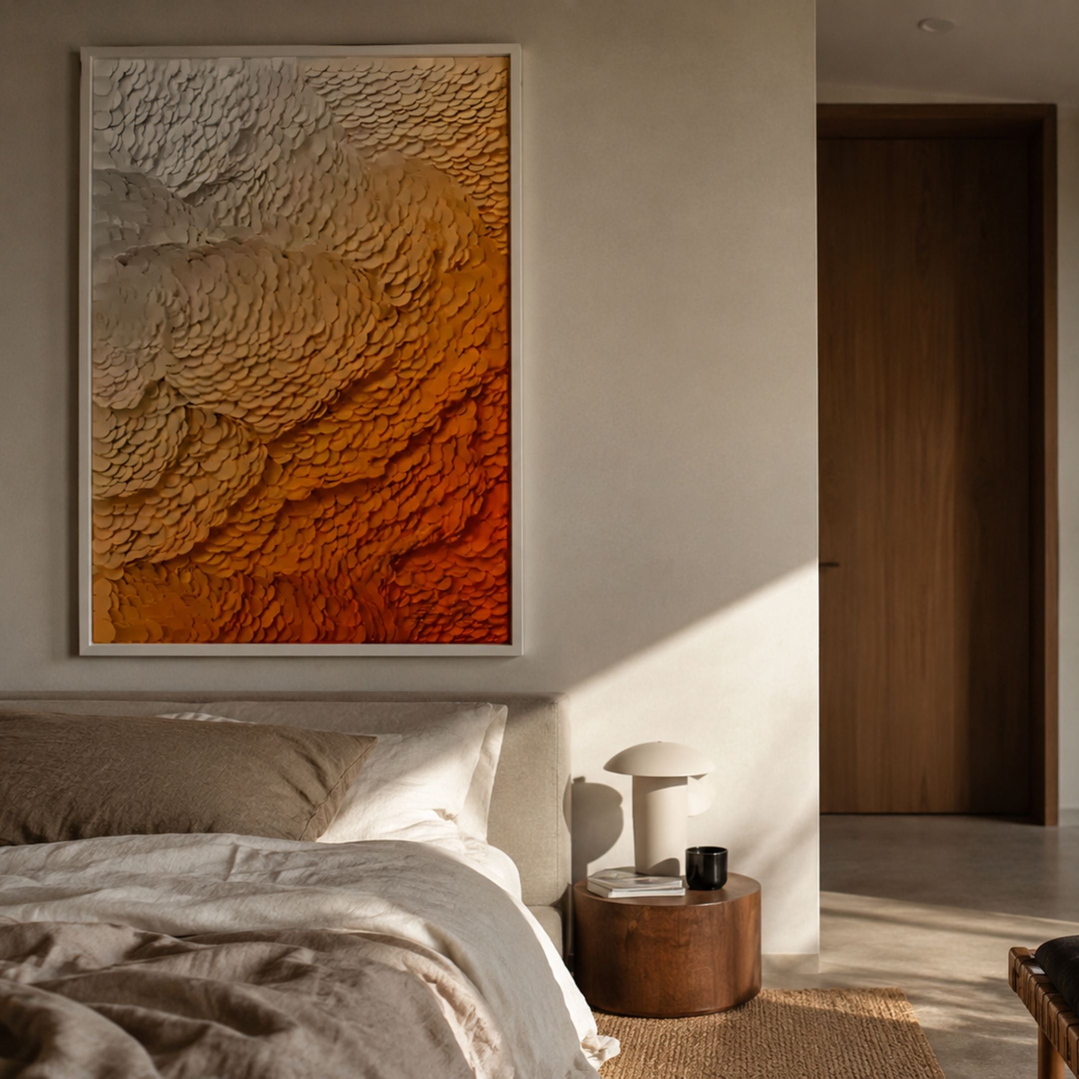 Petalwave Amber Fade Layered Bloom Leather 3D Wall Art in white frame above a linen bed, beside a wooden nightstand with lamp in a warm bedroom.