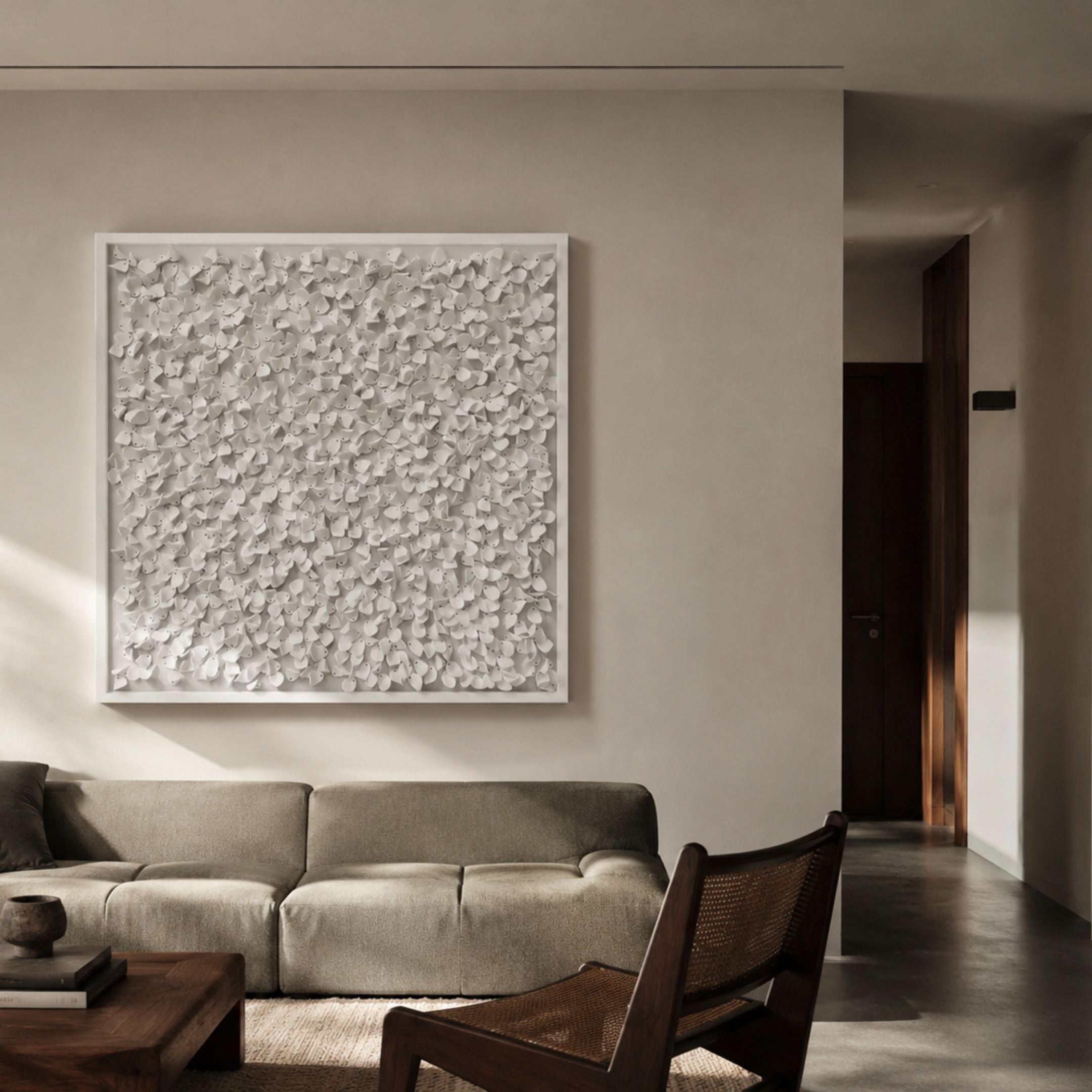 Bloom White Curved Petal Acrylic 3D Wall Art by Giant Sculptures displayed above a taupe sofa in a neutral living room with wooden cane chair and coffee table.