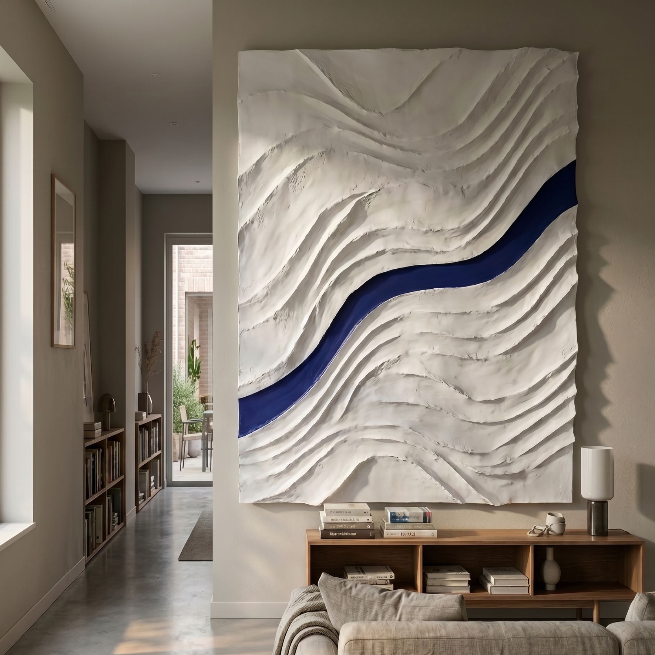 Evolva White & Blue Hand-Painted Wood Relief 3D Wall Art by Giant Sculptures, mounted above a wooden console in a hallway with bookshelves and a sofa.