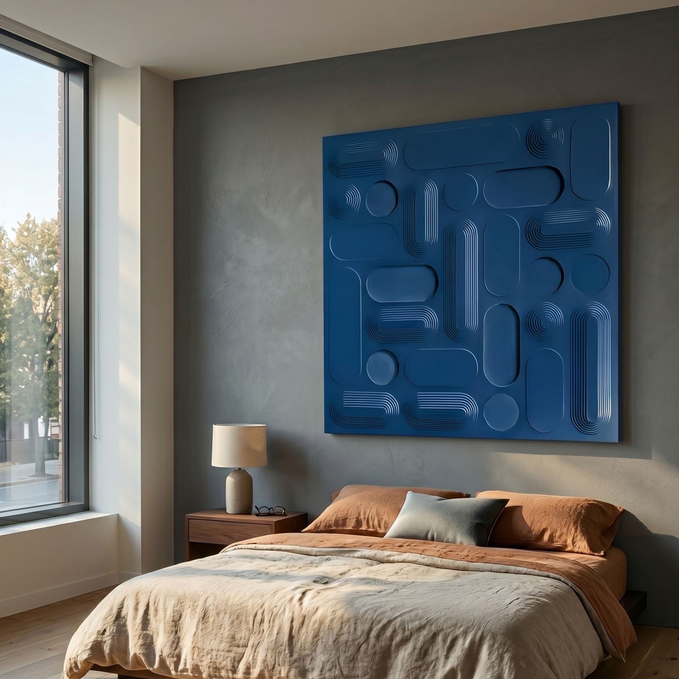 Grida Midnight Blue I Wood Carving 3D Wall Art by Giant Sculptures, a large square carved panel of rounded rectangles and circles, above a bed beside a window.