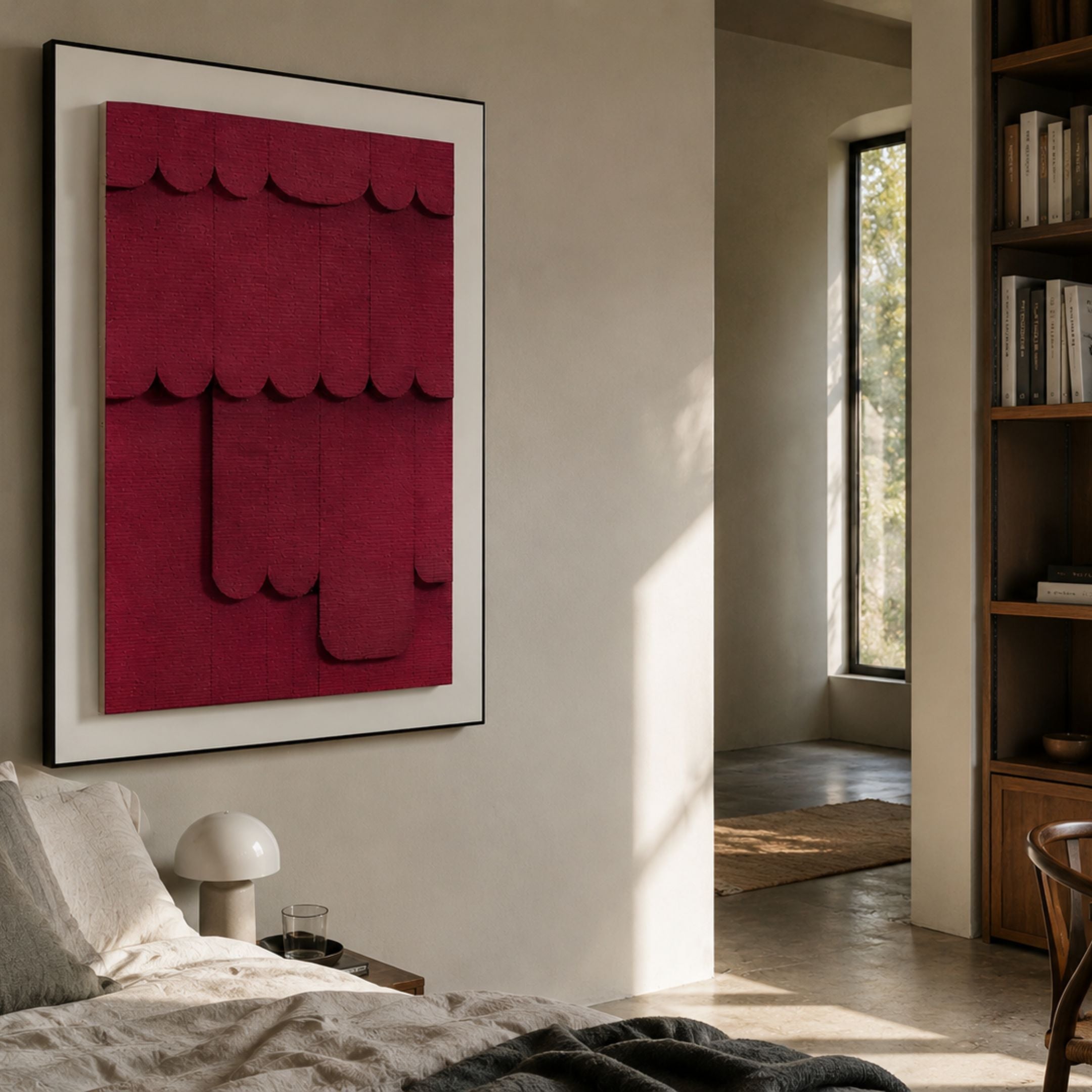 Cascala Crimson Layered Wood Carving 3D Wall Art by Giant Sculptures displayed above a bedside lamp in a sunlit bedroom with cream walls and wooden bookshelf.