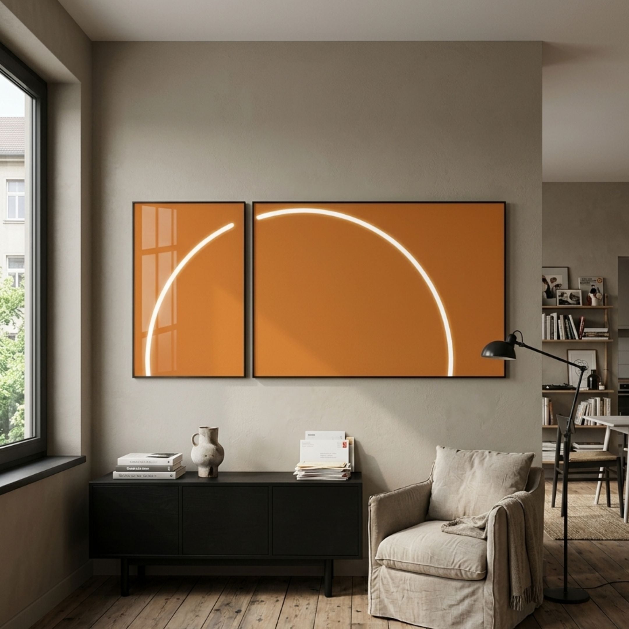 Enigma Amber Sunrise LED Wall Art by Giant Sculptures hung as a two-panel diptych with a glowing white arc on amber, above a black sideboard beside a linen armchair.